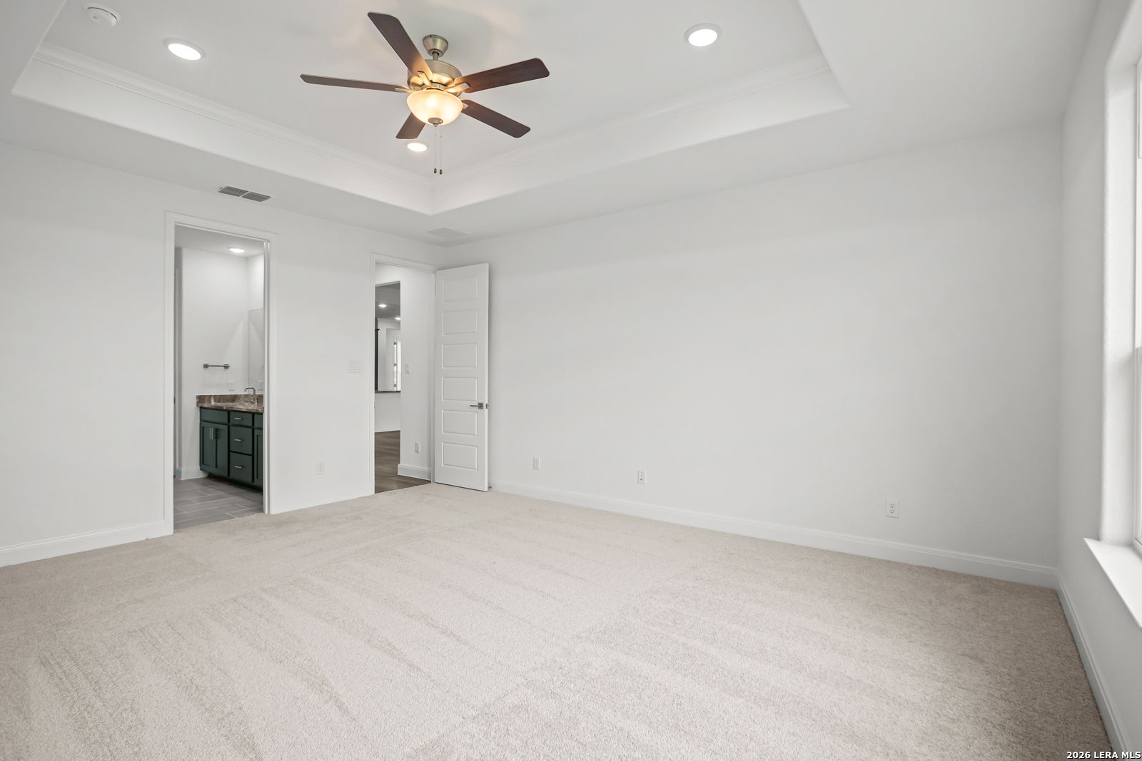 Primary bedroom with tray ceiling and en suite bathroom in The Lanier G floor plan at The Reserve at Potranco Oaks.