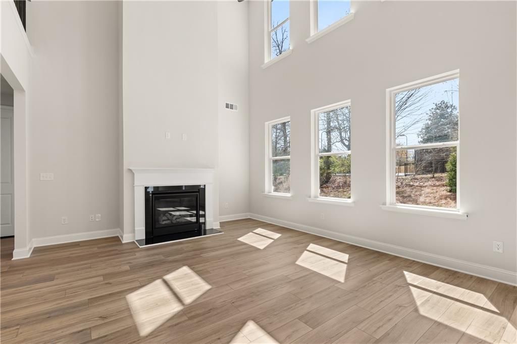 Bright family room with vaulted ceilings, gas fireplace, hardwood floors, and large windows overlooking wooded backyard in The Danbury C, Buford, GA