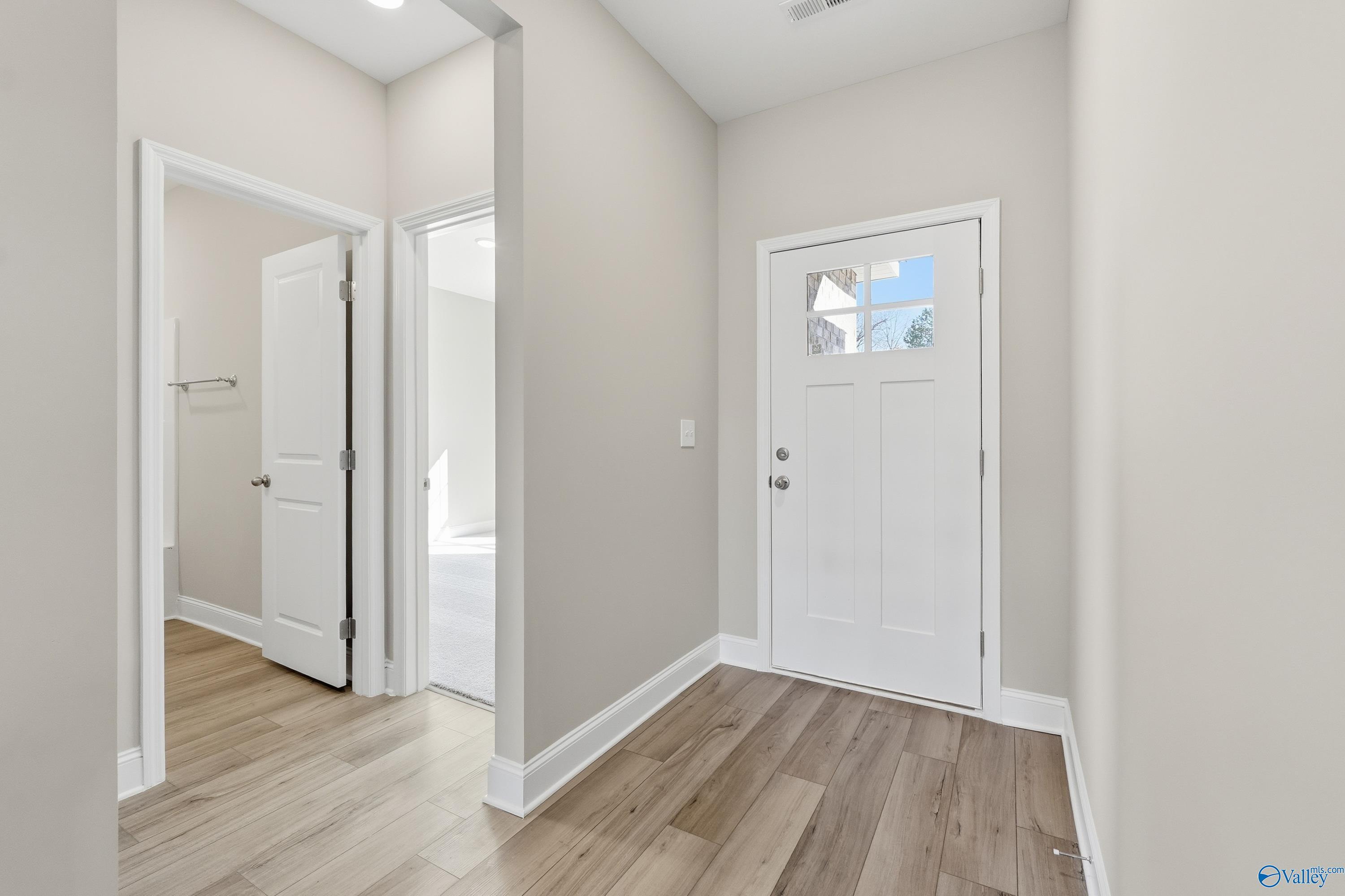 Bright entry hallway with beige walls, hardwood floors, bedroom and bath doors in Davidson Homes Franklin C, New Market AL