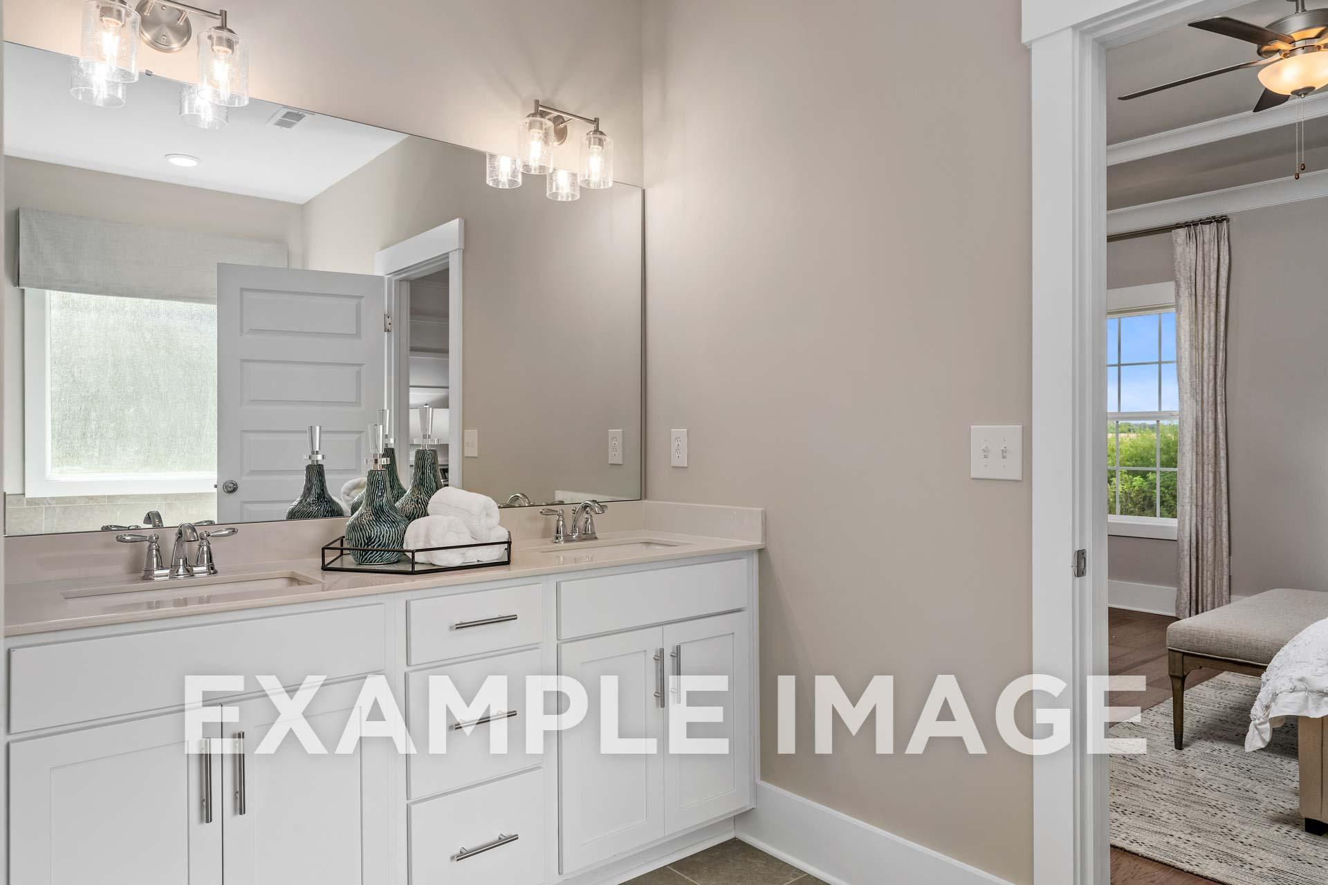 Spacious master bathroom in The Harrison B with double vanity, large lighted mirror, and neutral tones