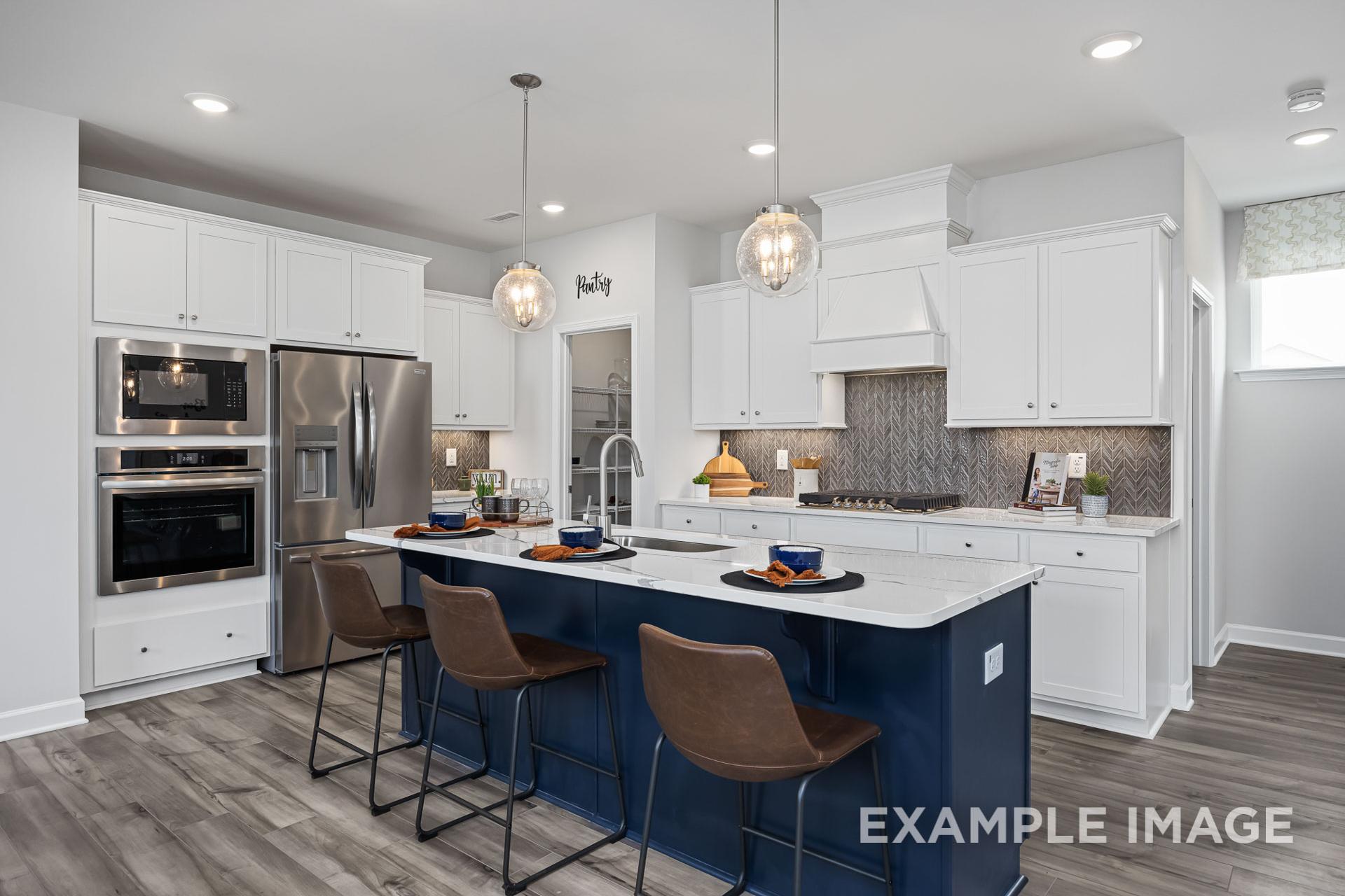 Modern kitchen at Woodland Crossing in Zebulon NC with white cabinets, navy island, bar stools, and stainless appliances