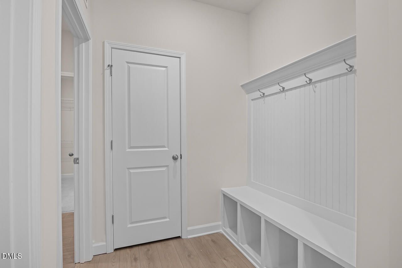 White beadboard mudroom with built-in bench, hooks, and storage in Davidson Homes The Cypress D II, Angier, NC