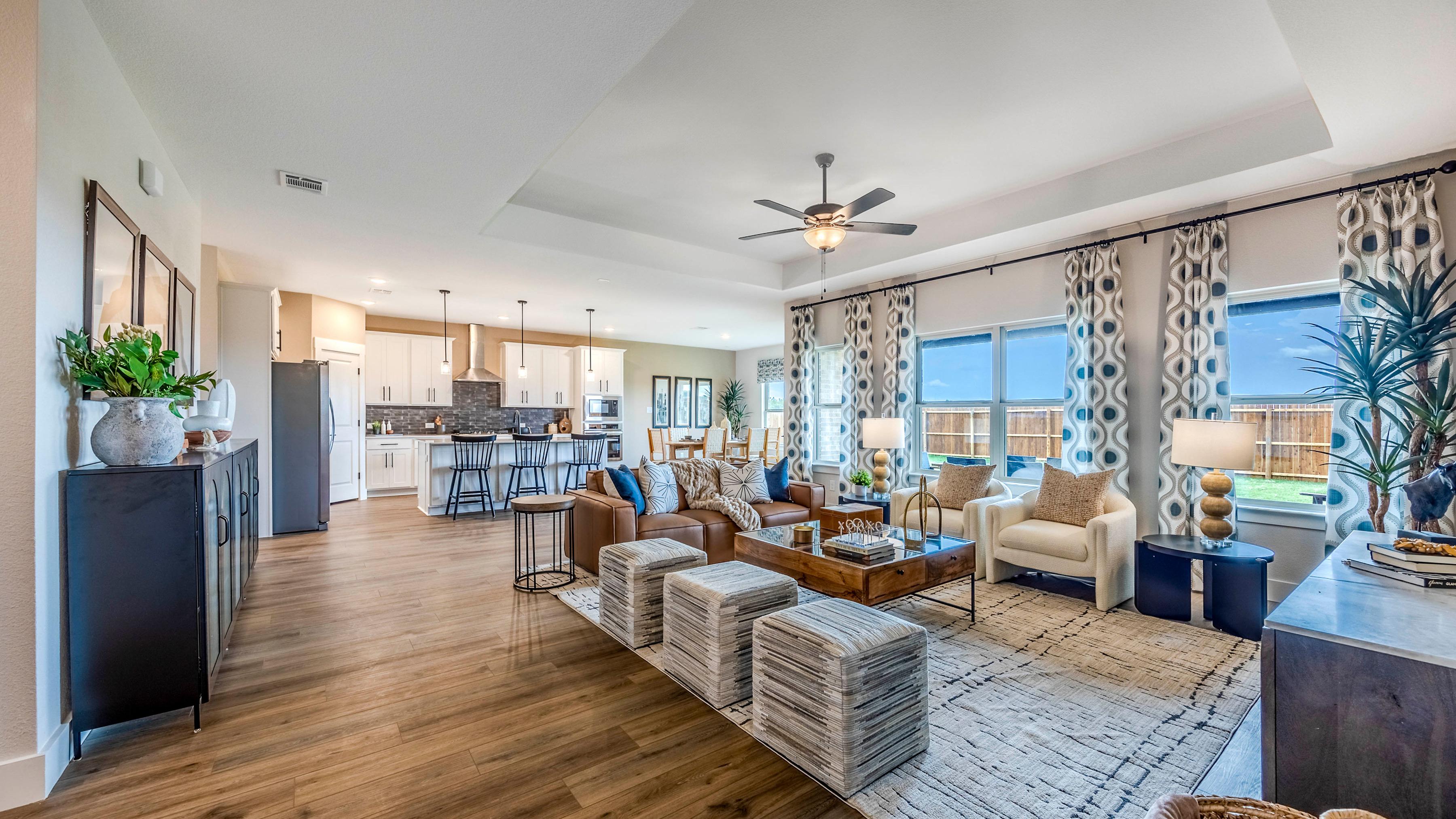 Open-concept living room and kitchen at Waverly Estates in Josephine, Texas with hardwood floors, modern furniture, and large windows