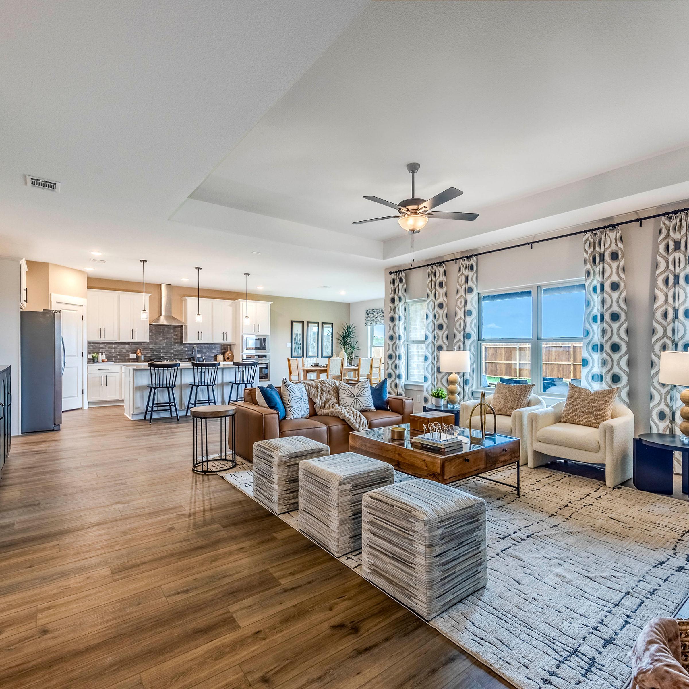 Open-concept living room and kitchen at Waverly Estates in Josephine, Texas with hardwood floors, modern furniture, and large windows