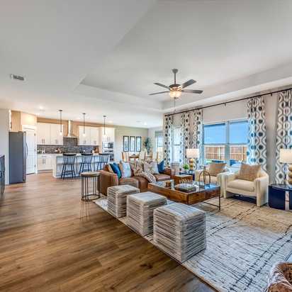 Open-concept living room and kitchen at Waverly Estates in Josephine, Texas with hardwood floors, modern furniture, and large windows