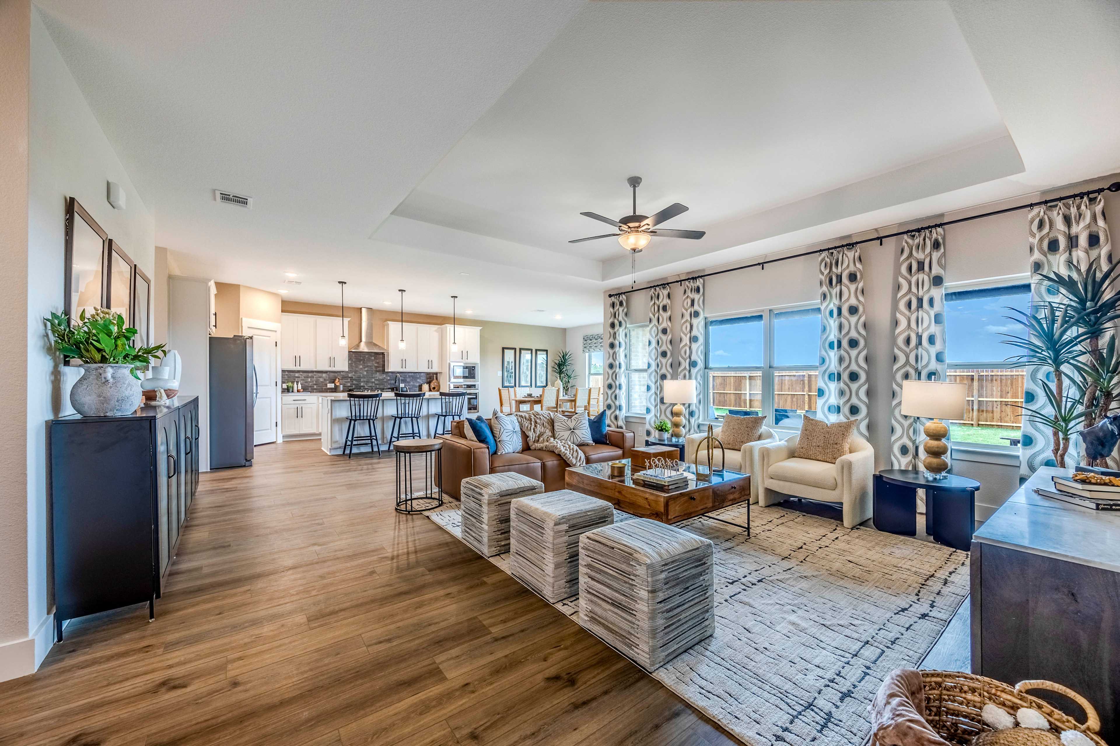 Spacious open-concept living room and kitchen at Waverly Estates in Josephine TX with hardwood floors, ceiling fans, and modern seating