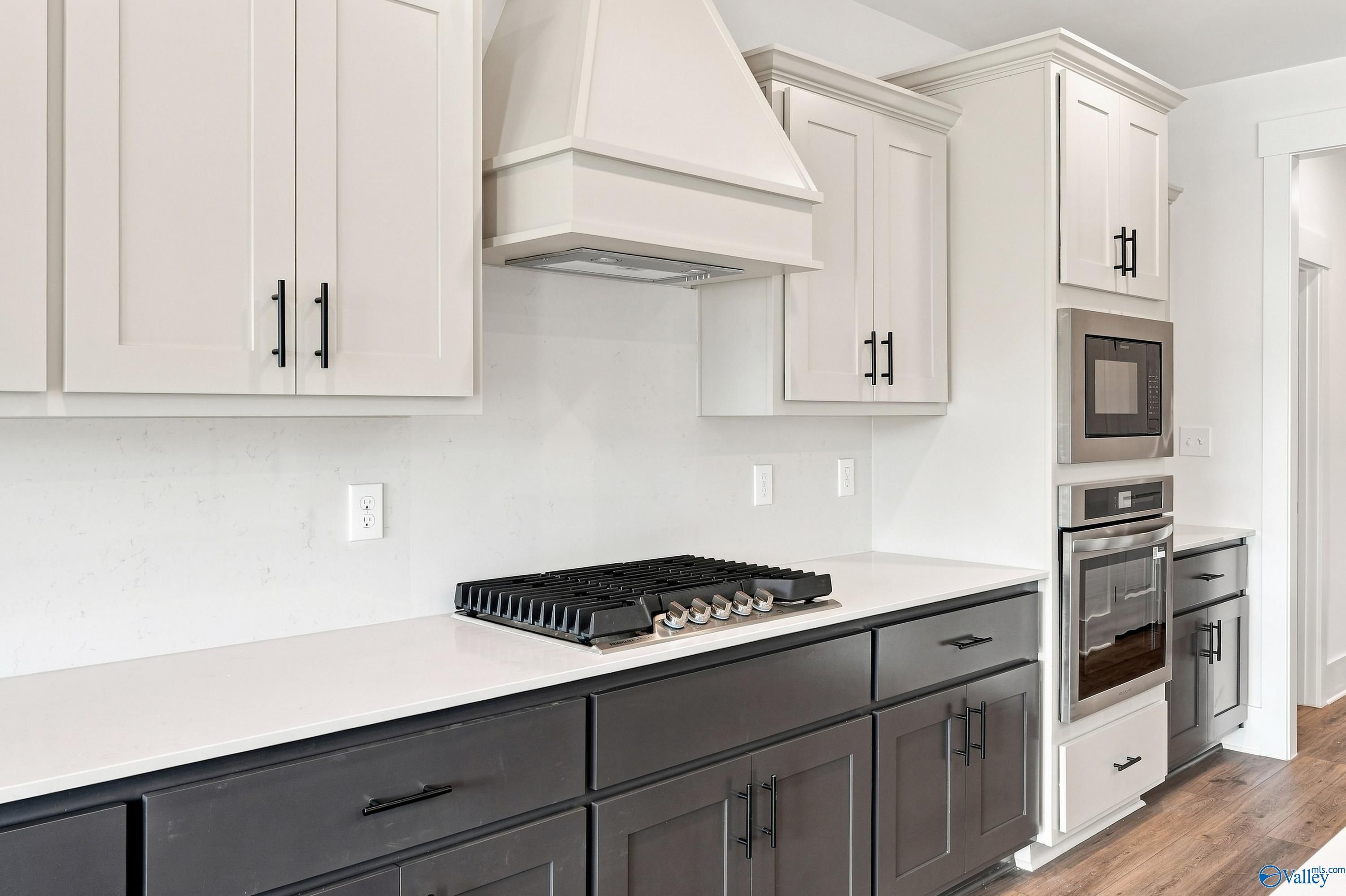 Two-tone kitchen with gas cooktop, white range hood, and stainless wall oven in Davidson Homes Valencia plan, Huntsville, AL