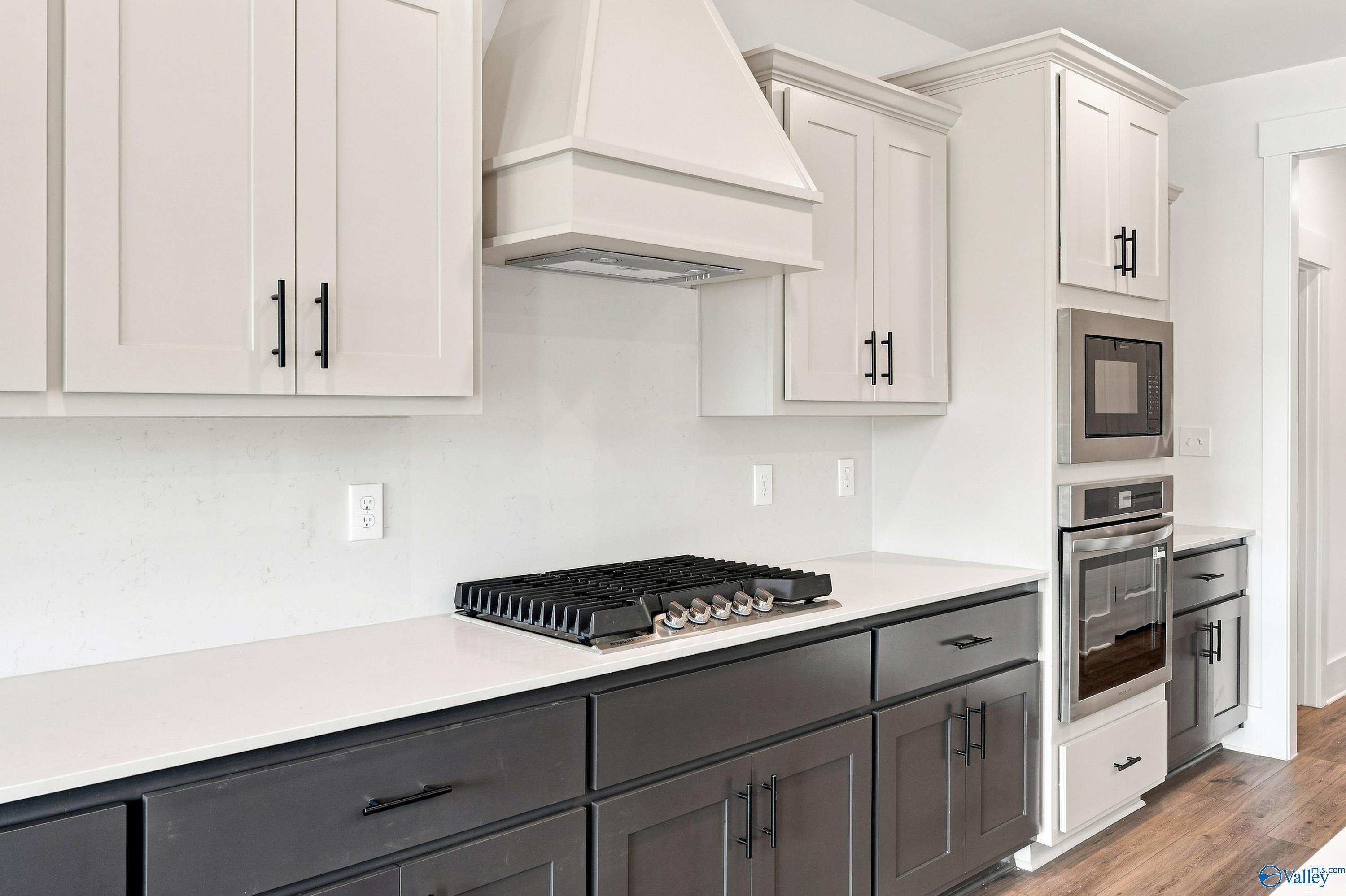 Two-tone kitchen with gas cooktop, white range hood, and stainless wall oven in Davidson Homes Valencia plan, Huntsville, AL