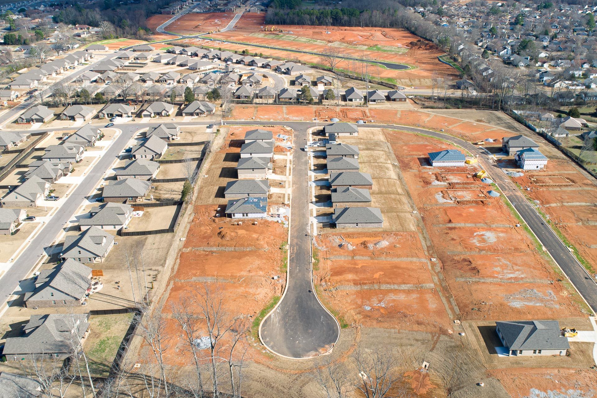 Aerial view of new single-family homes in Heritage Heights, Madison Alabama with red clay lots and developing streets
