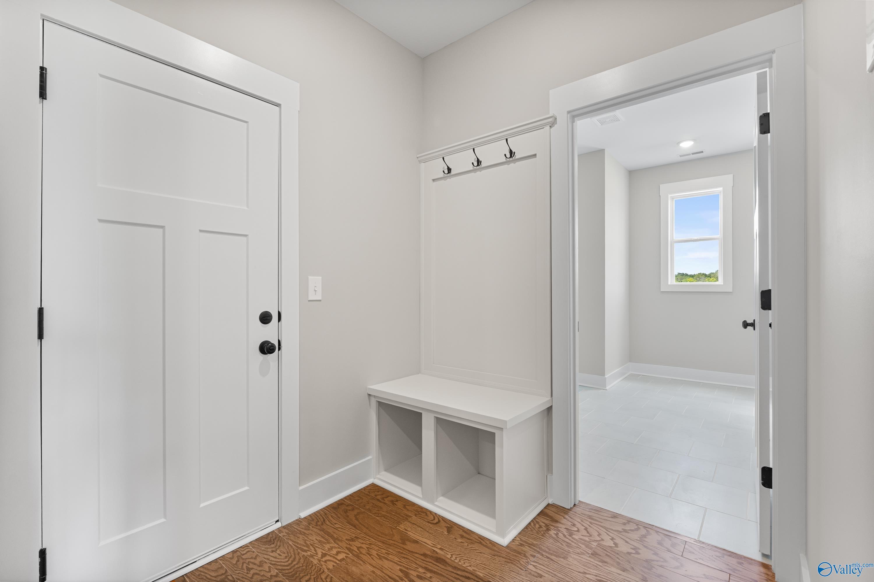 Inviting mudroom with built-in white bench, cubbies, coat hooks, and double doors in Davidson Homes The Arcadia, Riverton Preserve, Huntsville AL