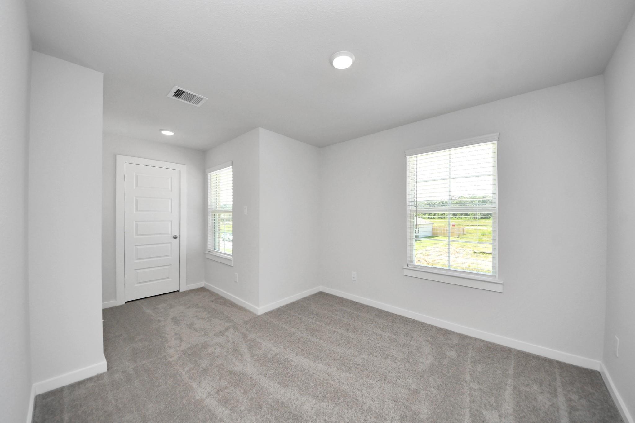 Bright, carpeted bedroom with natural light in The Brazos F floor plan at Liberty Estates, Cleveland, Texas.