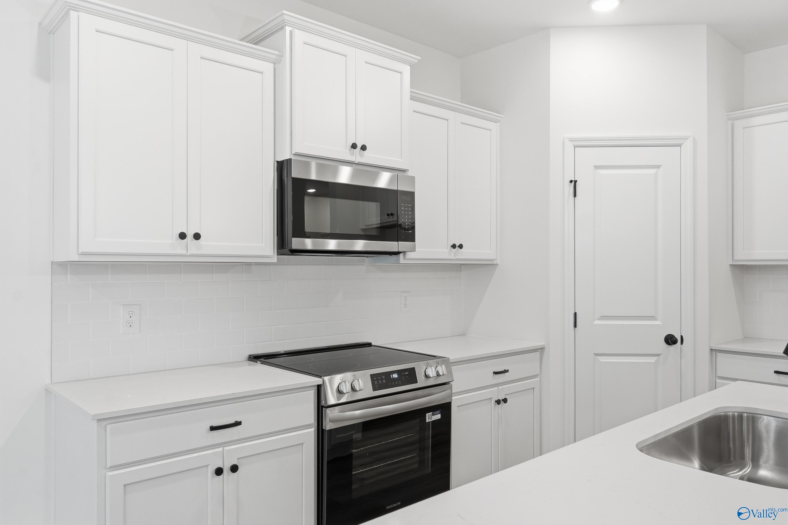 Modern kitchen with white cabinets, stainless steel appliances, and subway tile backsplash in The Asheville C floor plan.