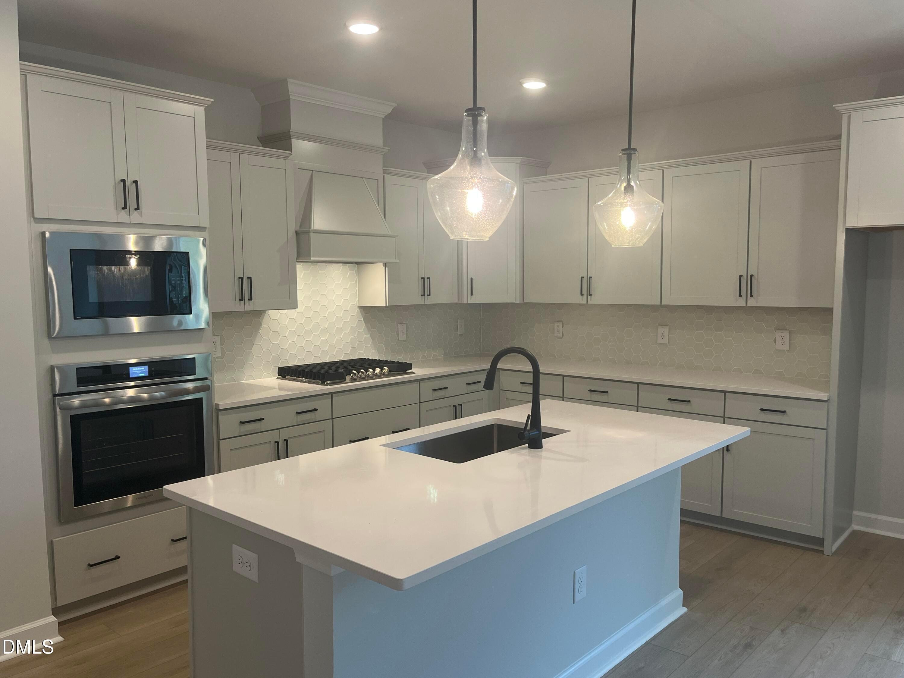Modern kitchen with white shaker cabinets, quartz countertops, stainless steel appliances, hexagon backsplash in Davidson Homes The Birch II E, Wake Forest, NC