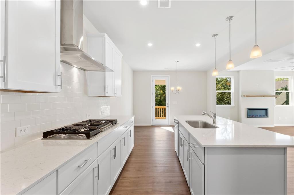 Modern white kitchen with quartz island, gas range, subway tile backsplash in The Willow B by Davidson Homes, Riverwood, Dallas, GA