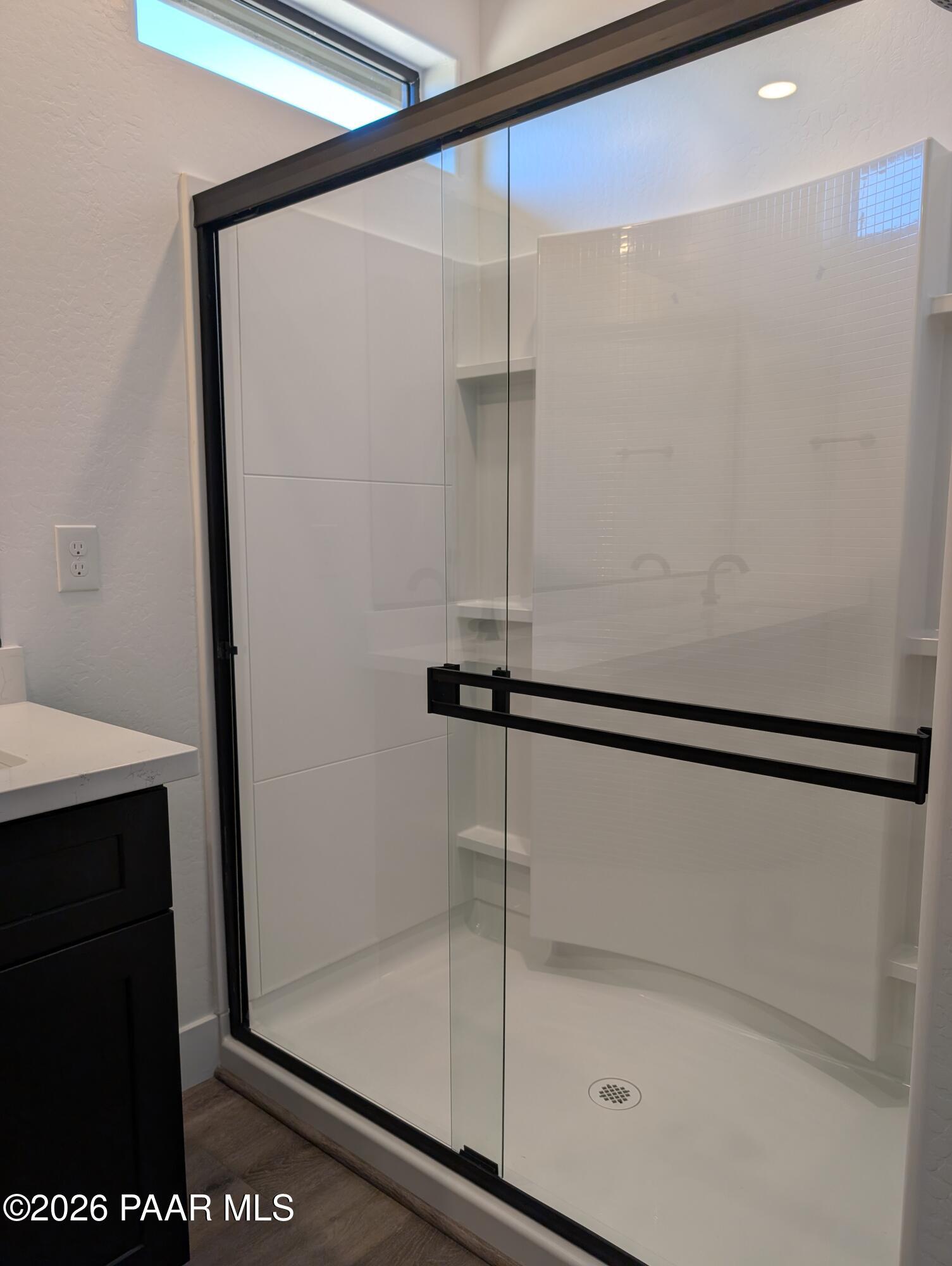 Frameless glass shower with white subway tiles, niche shelf, and curved wall in master bath of Davidson Homes The Sheridan II G, Prescott, Arizona