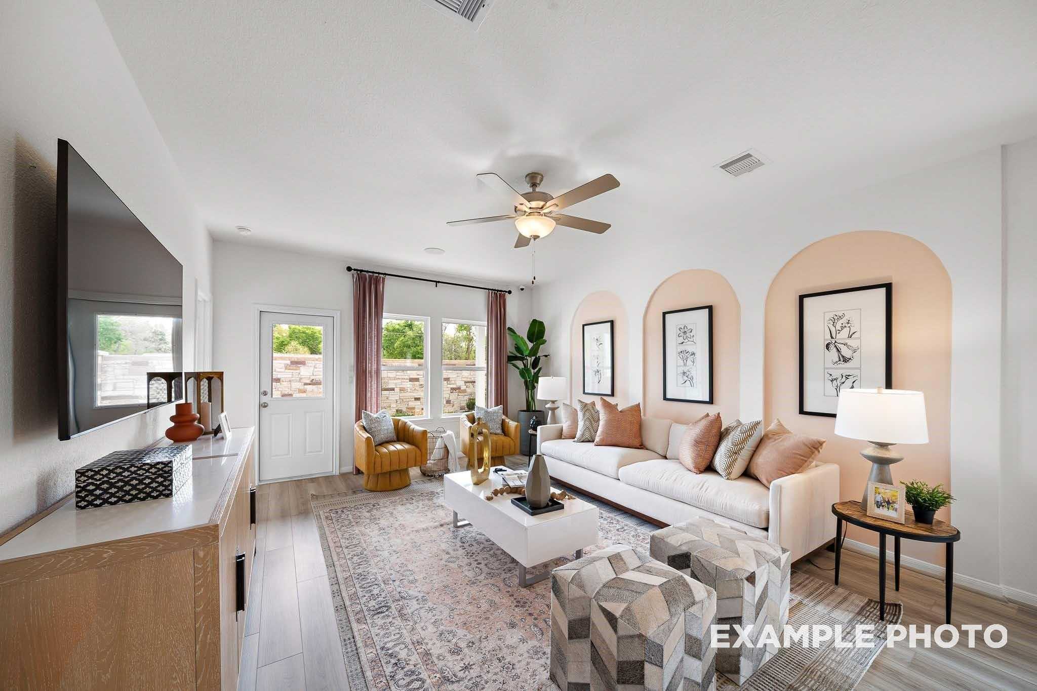 Cozy modern living room with beige sofa, yellow armchairs, arched niches, and ceiling fan in Davidson Homes The Sabine F, Magnolia, Texas