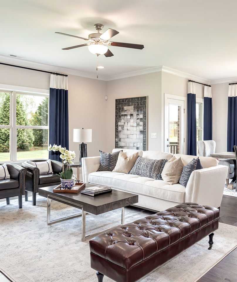 Spacious open-concept living room in Williams Pointe, Huntsville AL with white sofa, blue curtains, hardwood floors, and dining area