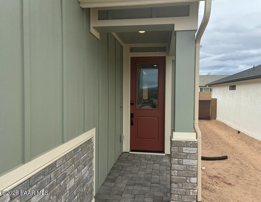 Modern front entrance featuring red glass door, sage green siding, and brick accents on The Malibu B in Prescott, AZ