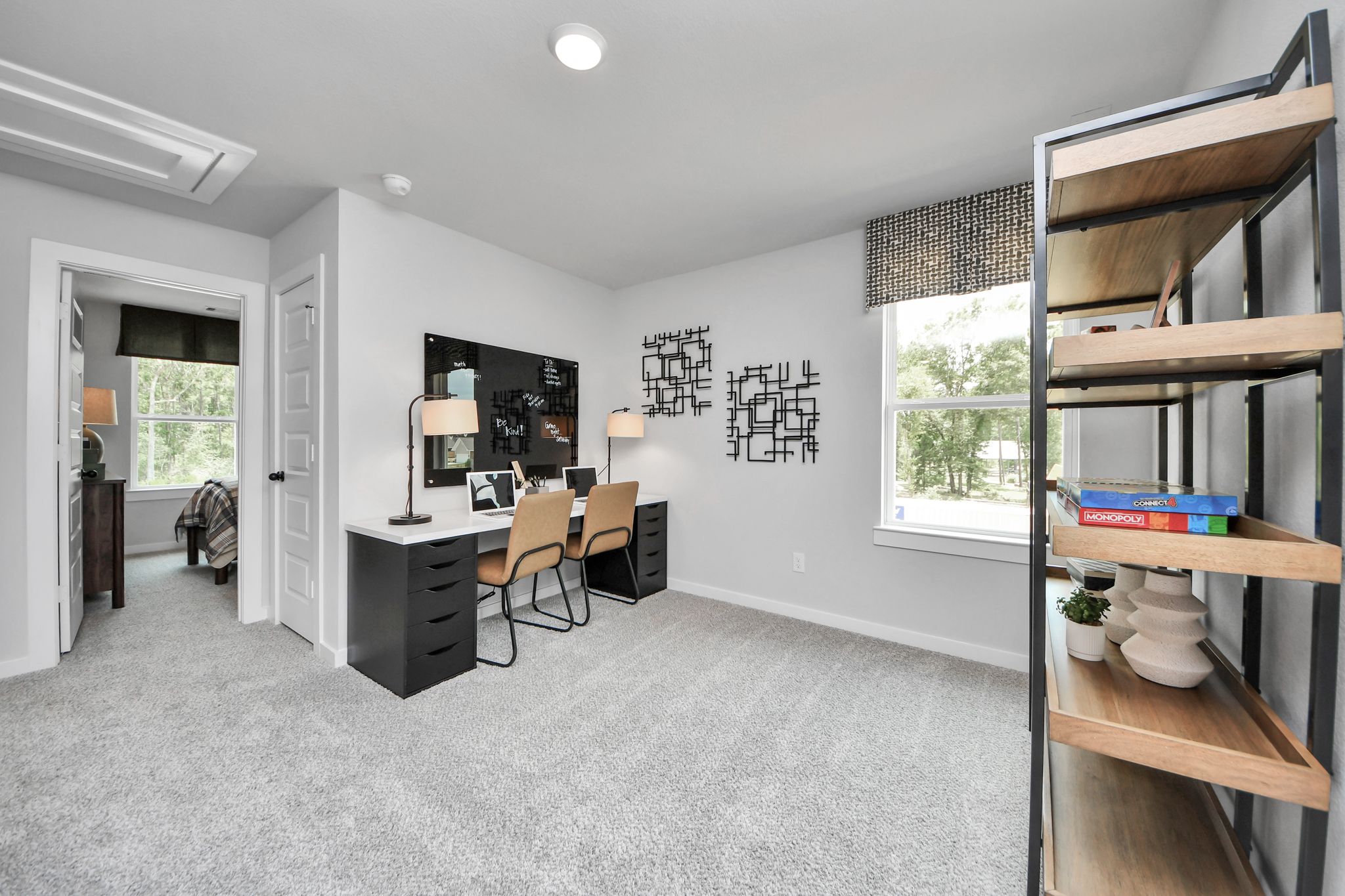 Modern home office with dual desk setup at Robins Landing in Houston, TX by Davidson Homes featuring carpeted flooring.