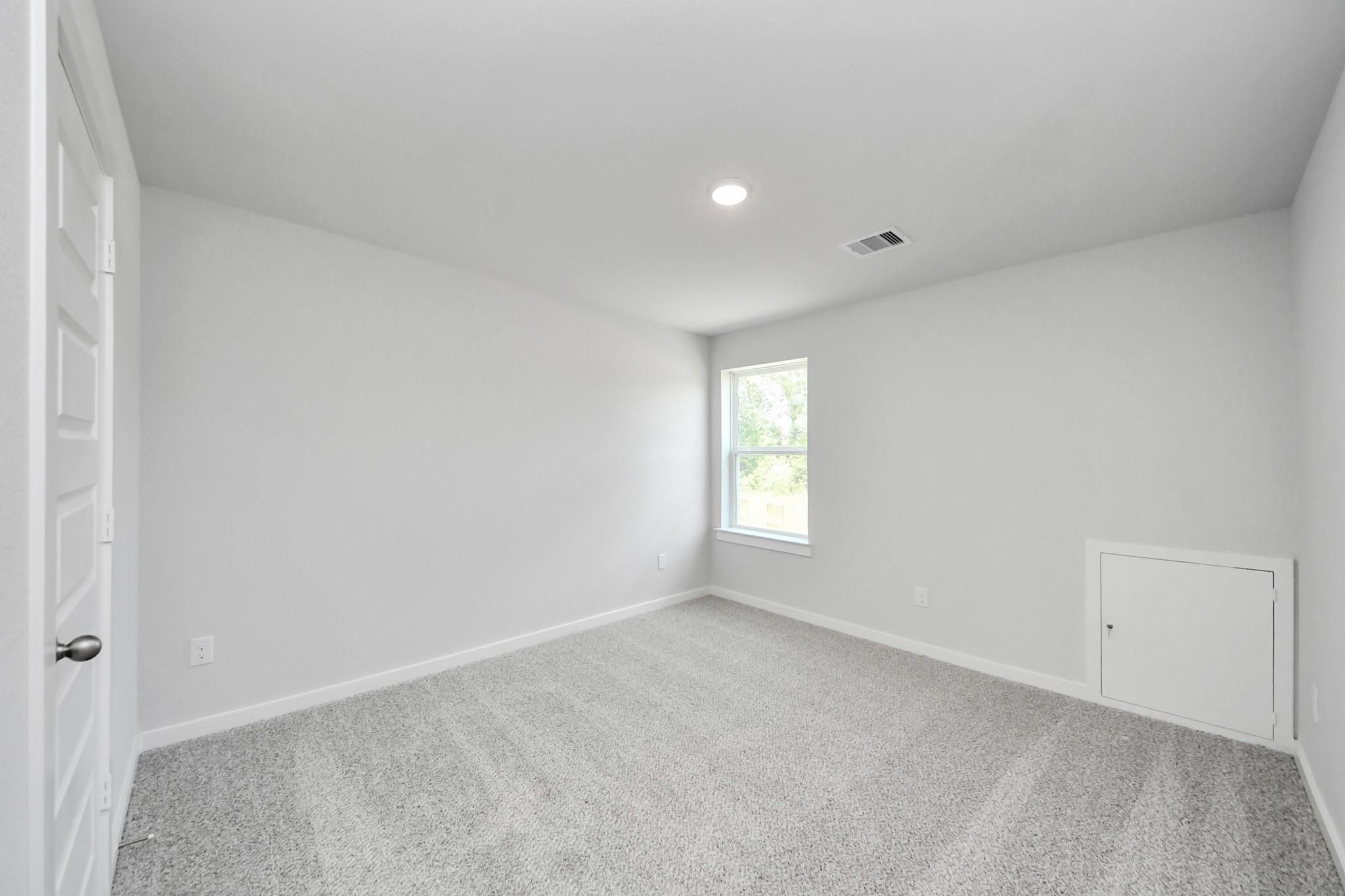Spacious bedroom with neutral carpet and storage access in The Sabine F floor plan at Liberty Estates, Cleveland, Texas.