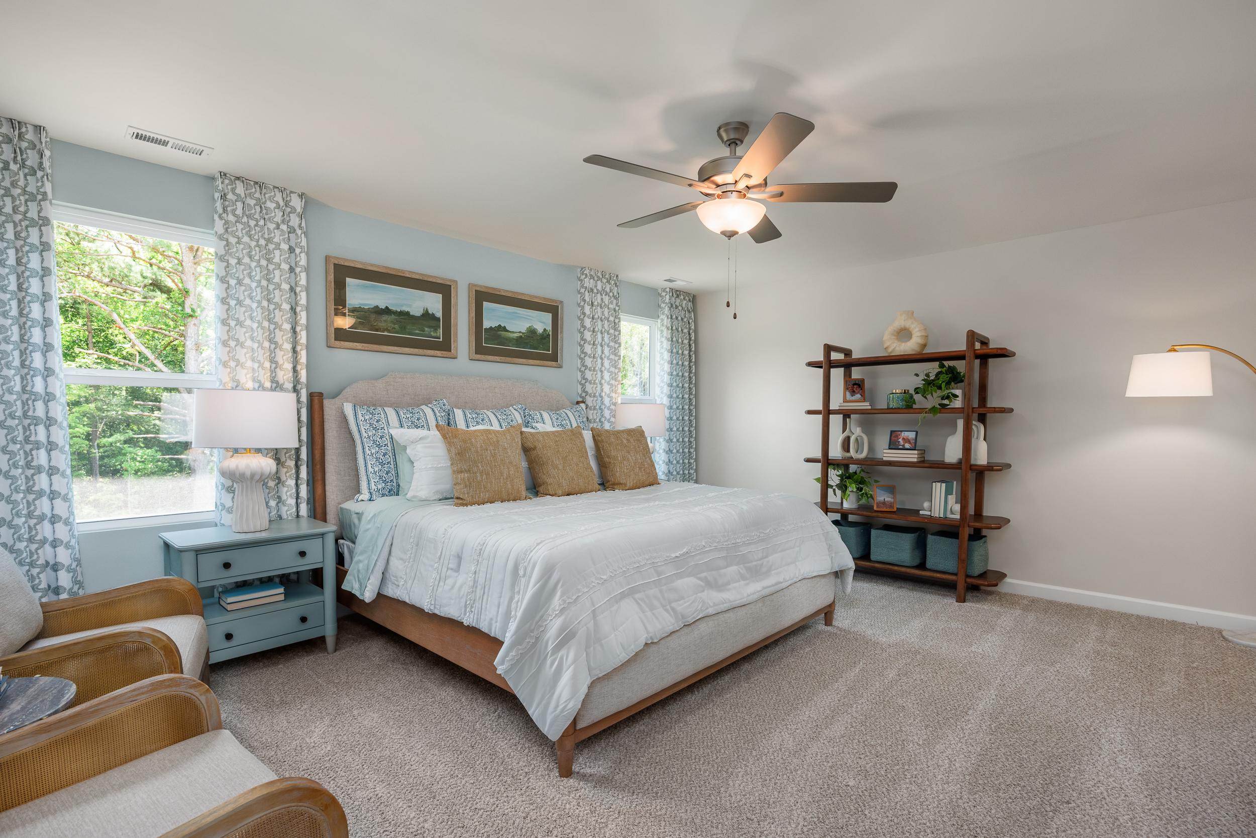 Spacious primary bedroom at Retreat at North Main in Lillington NC with king bed, ceiling fan, and modern furnishings by Davidson Homes