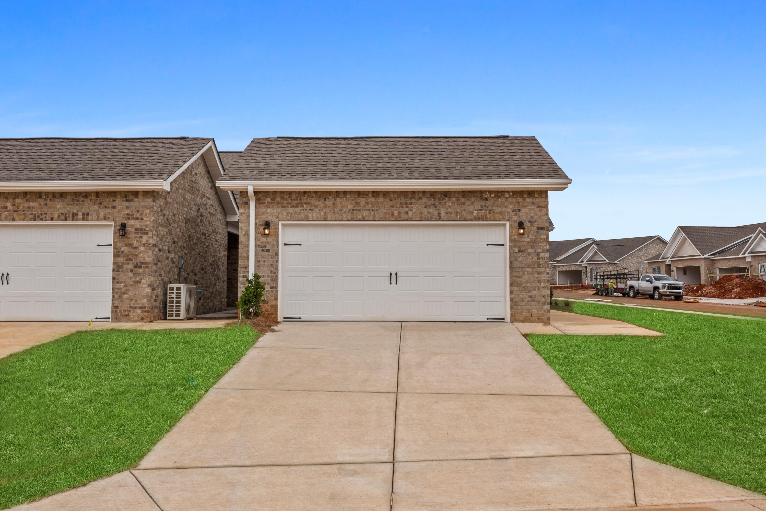 Brick exterior of The Copeland 2-story multi-family home with 2-car garage, driveway, and green lawn in Madison, Alabama