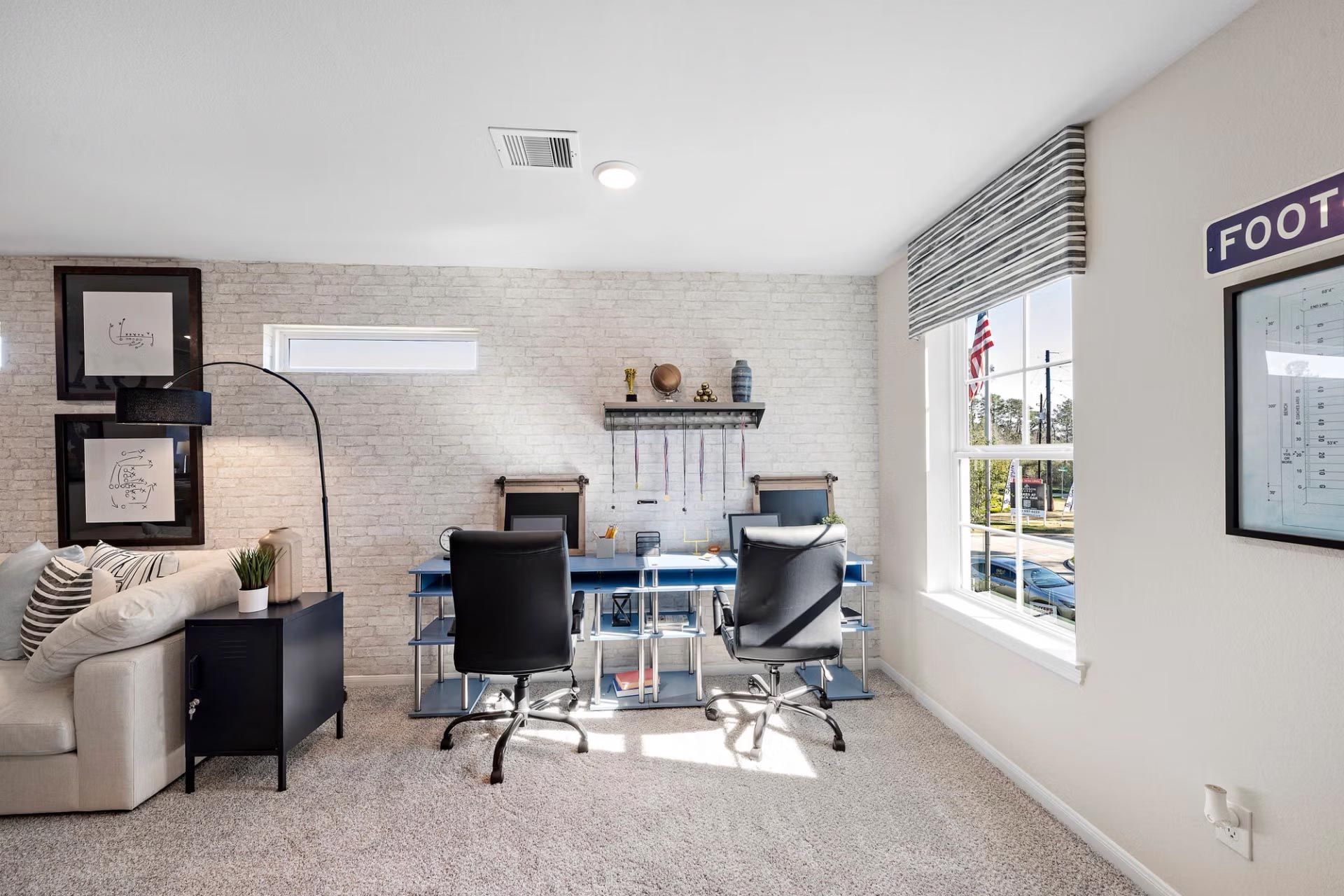 Spacious bonus room with dual desks, ergonomic chairs, foosball sign, and large windows at Saddle Creek Ranch in Cibolo, Texas