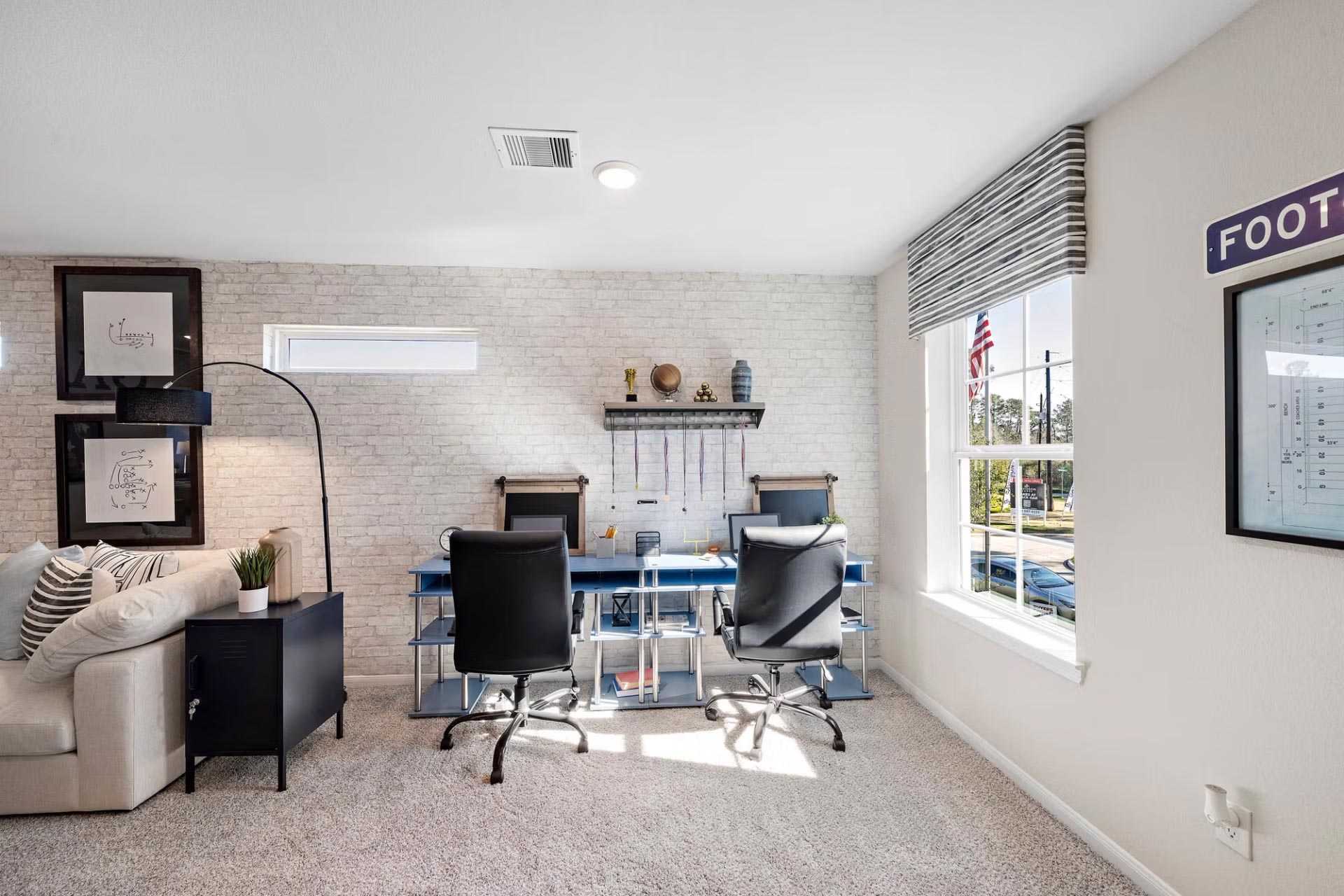 Spacious bonus room with dual desks, ergonomic chairs, foosball sign, and large windows at Saddle Creek Ranch in Cibolo, Texas