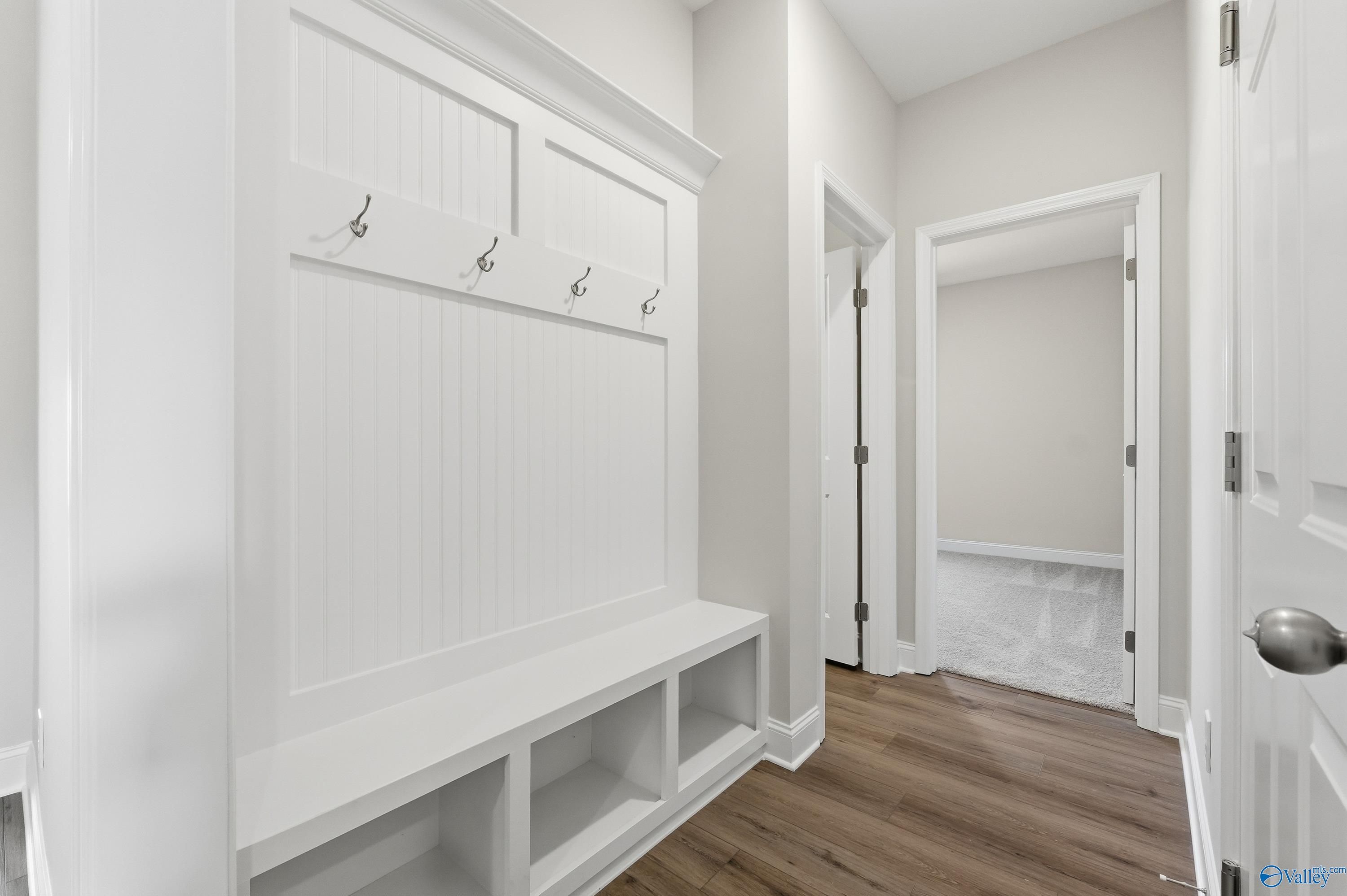 White built-in mudroom with coat hooks and storage bench in Davidson Homes Everett floor plan, Creekside, Harvest, Alabama