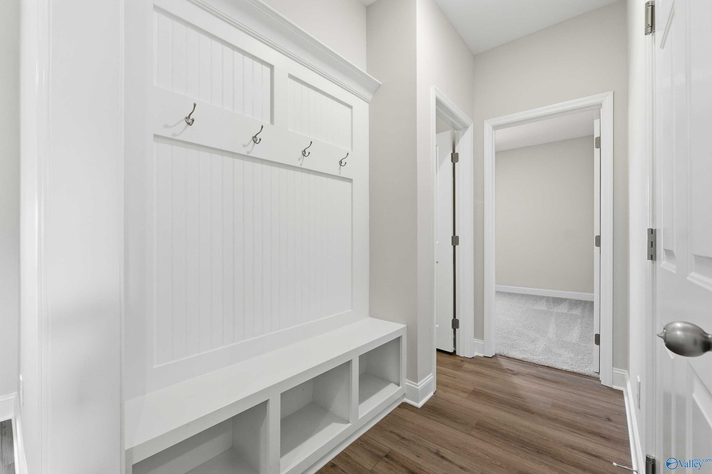 White built-in mudroom with coat hooks and storage bench in Davidson Homes Everett floor plan, Creekside, Harvest, Alabama