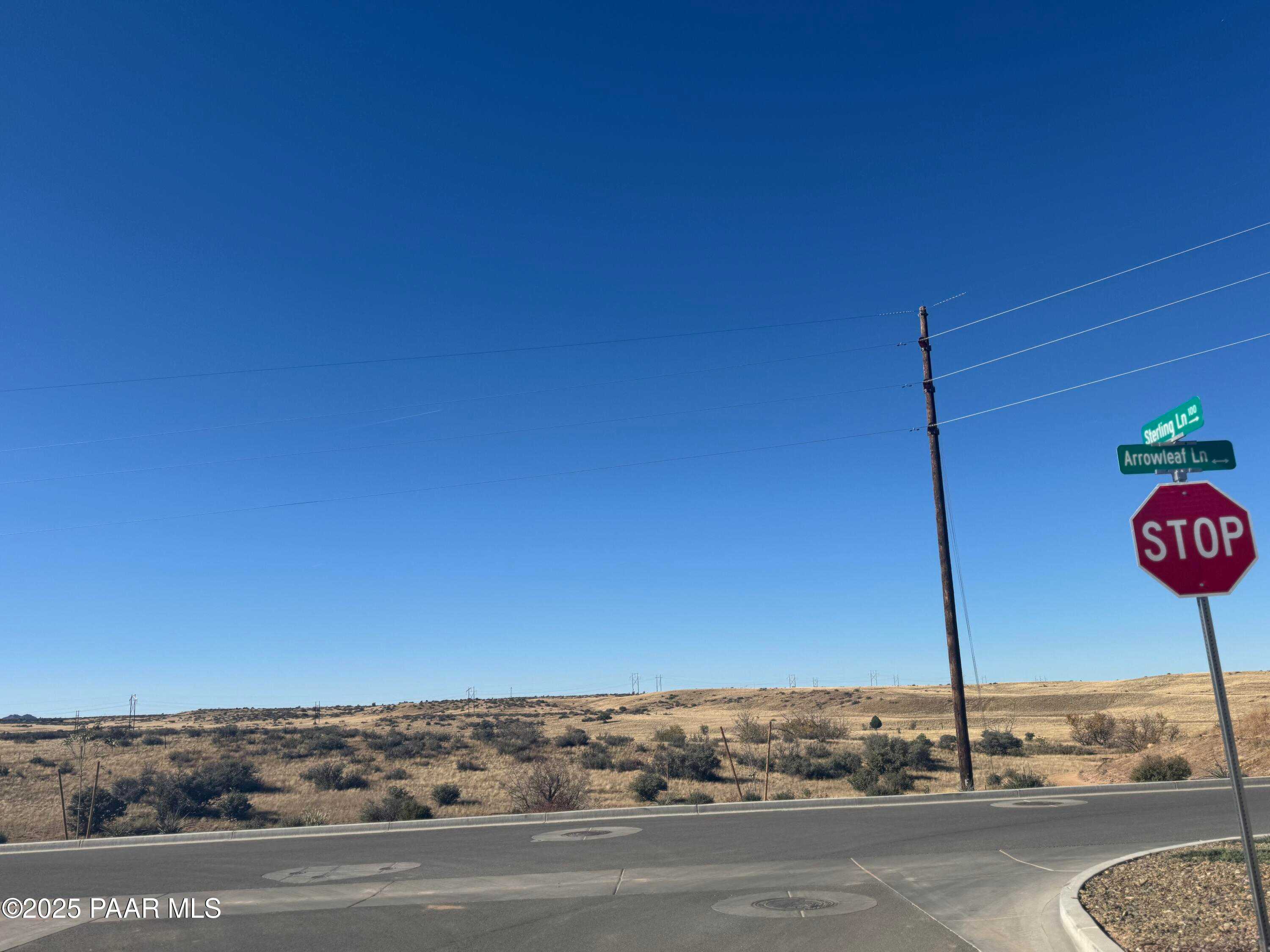 Desert street intersection with stop sign and Arroyo Lane sign under clear blue sky in Westwood, Prescott, Arizona