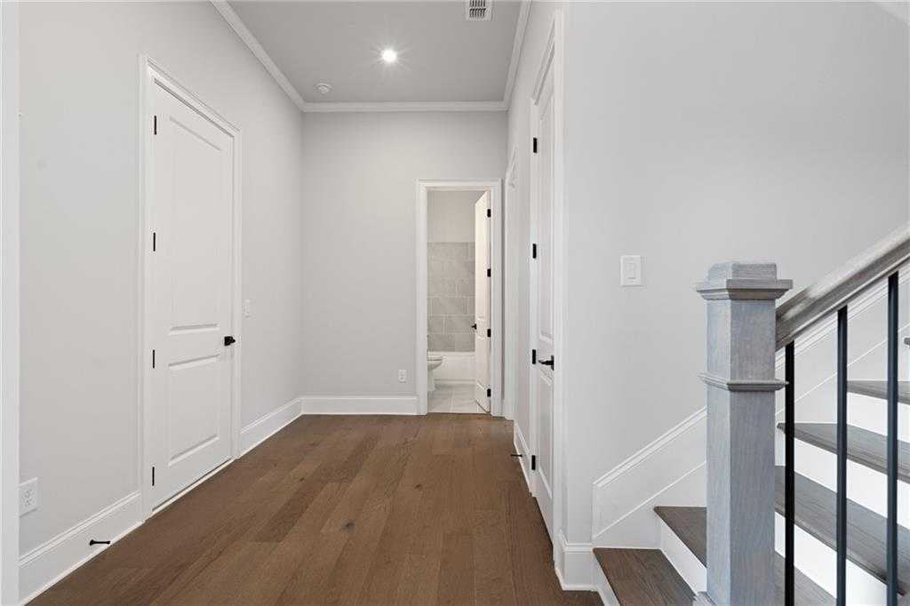 Bright upstairs hallway with hardwood floors, white doors to bedrooms and bath, elegant staircase in Davidson Homes The Seaside B, Woodstock, GA