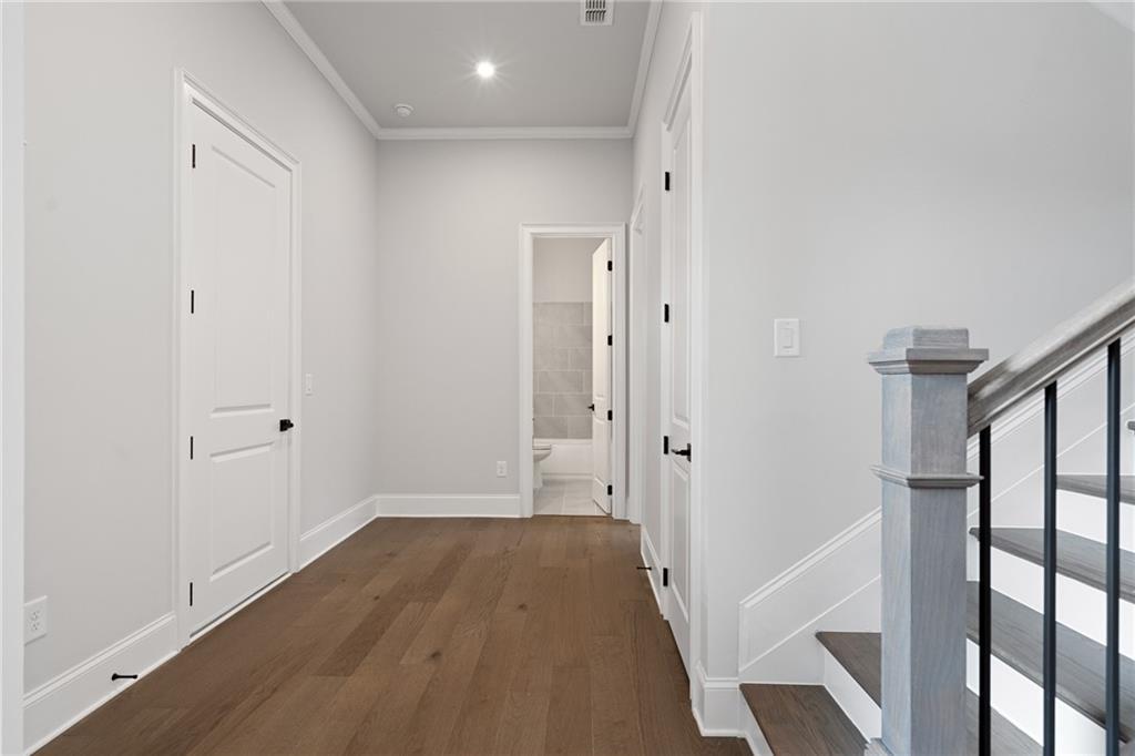 Bright upstairs hallway with hardwood floors, white doors to bedrooms and bath, elegant staircase in Davidson Homes The Seaside B, Woodstock, GA