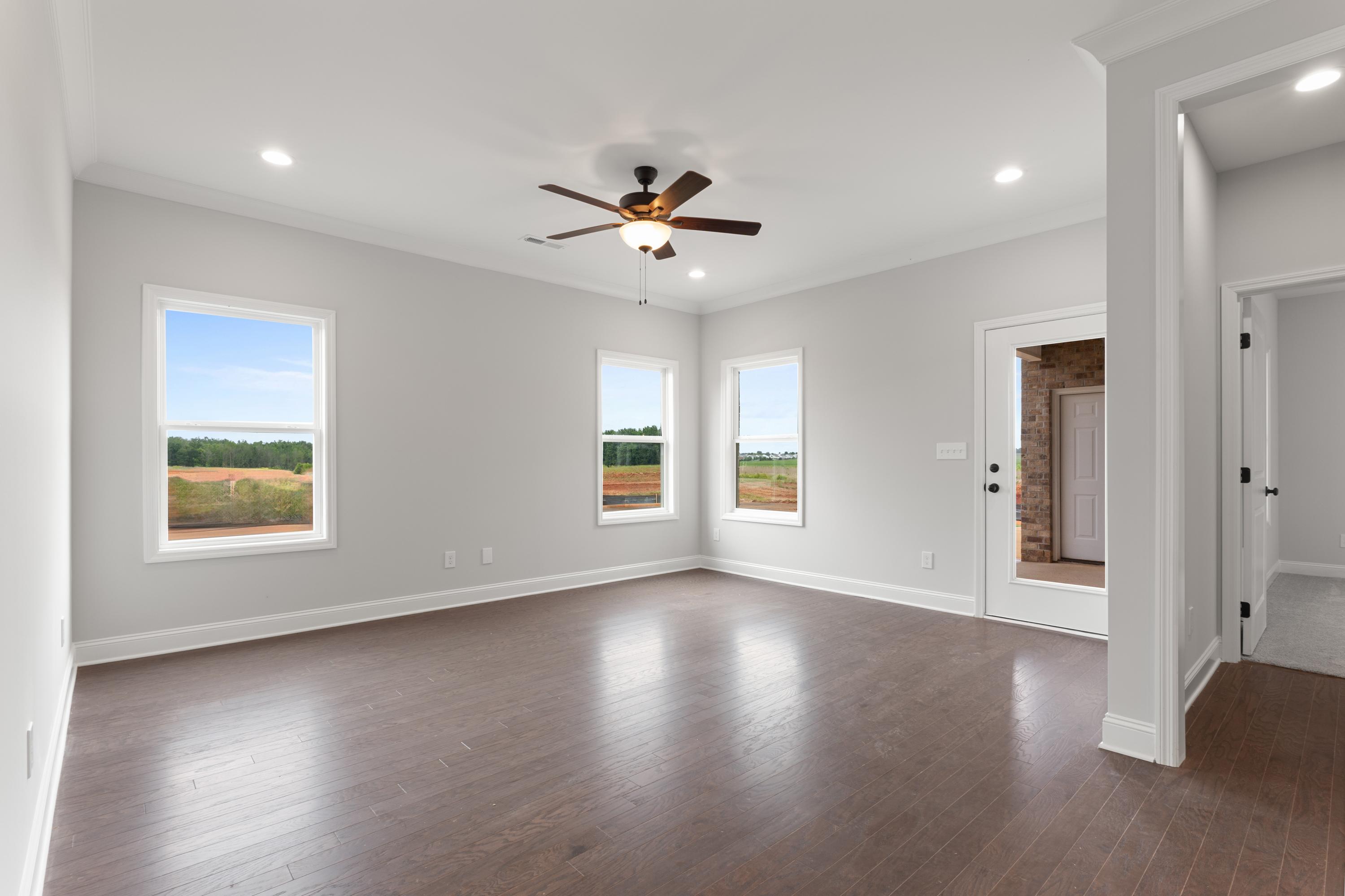 Spacious master suite in The Copeland with large windows overlooking rural fields, ceiling fan, hardwood floors by Davidson Homes in Madison, Alabama