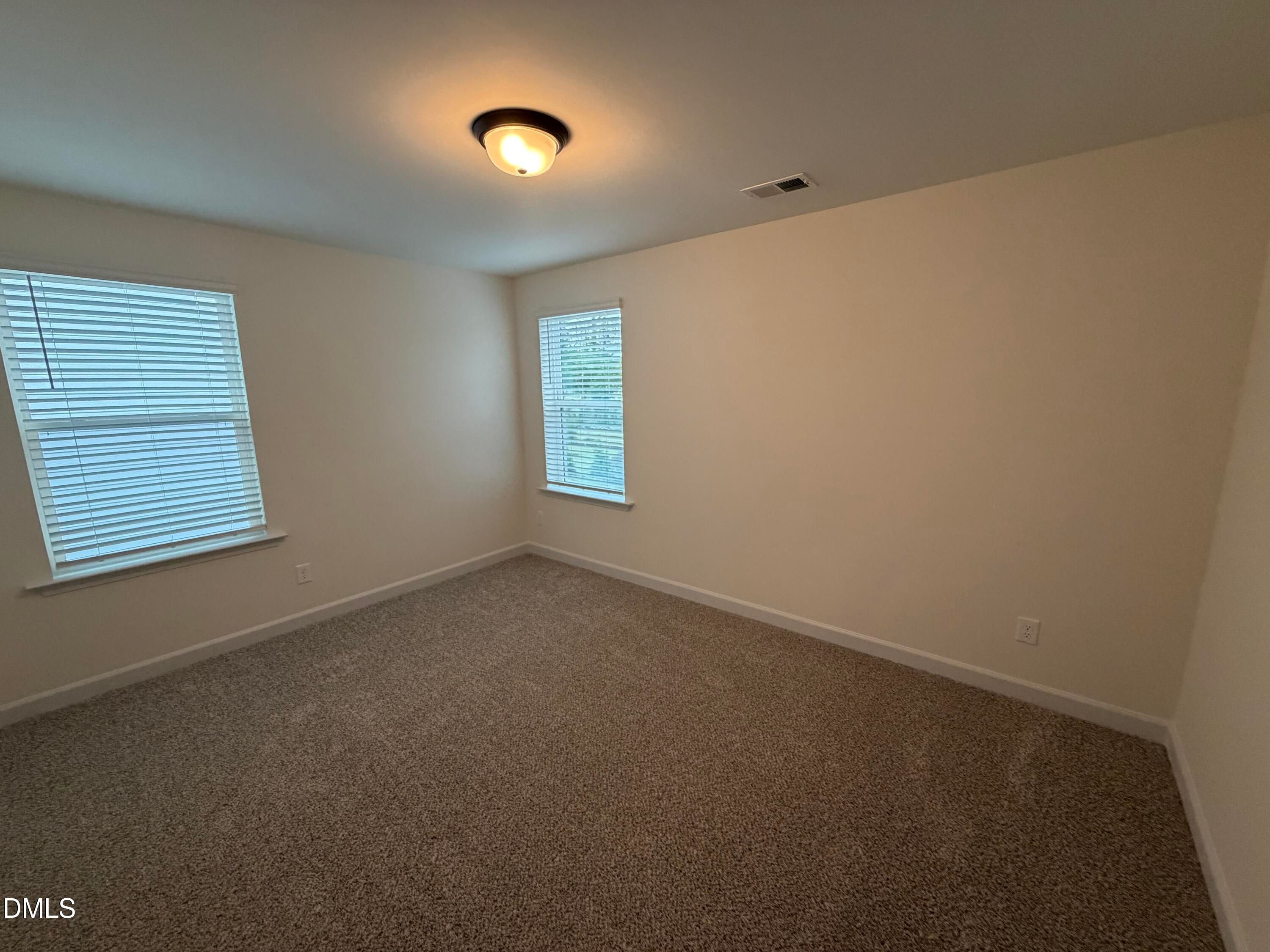 Bright carpeted bedroom with two windows, flush-mount lighting, and neutral walls in Davidson Homes The Ashport M, Wendell Ridge, NC