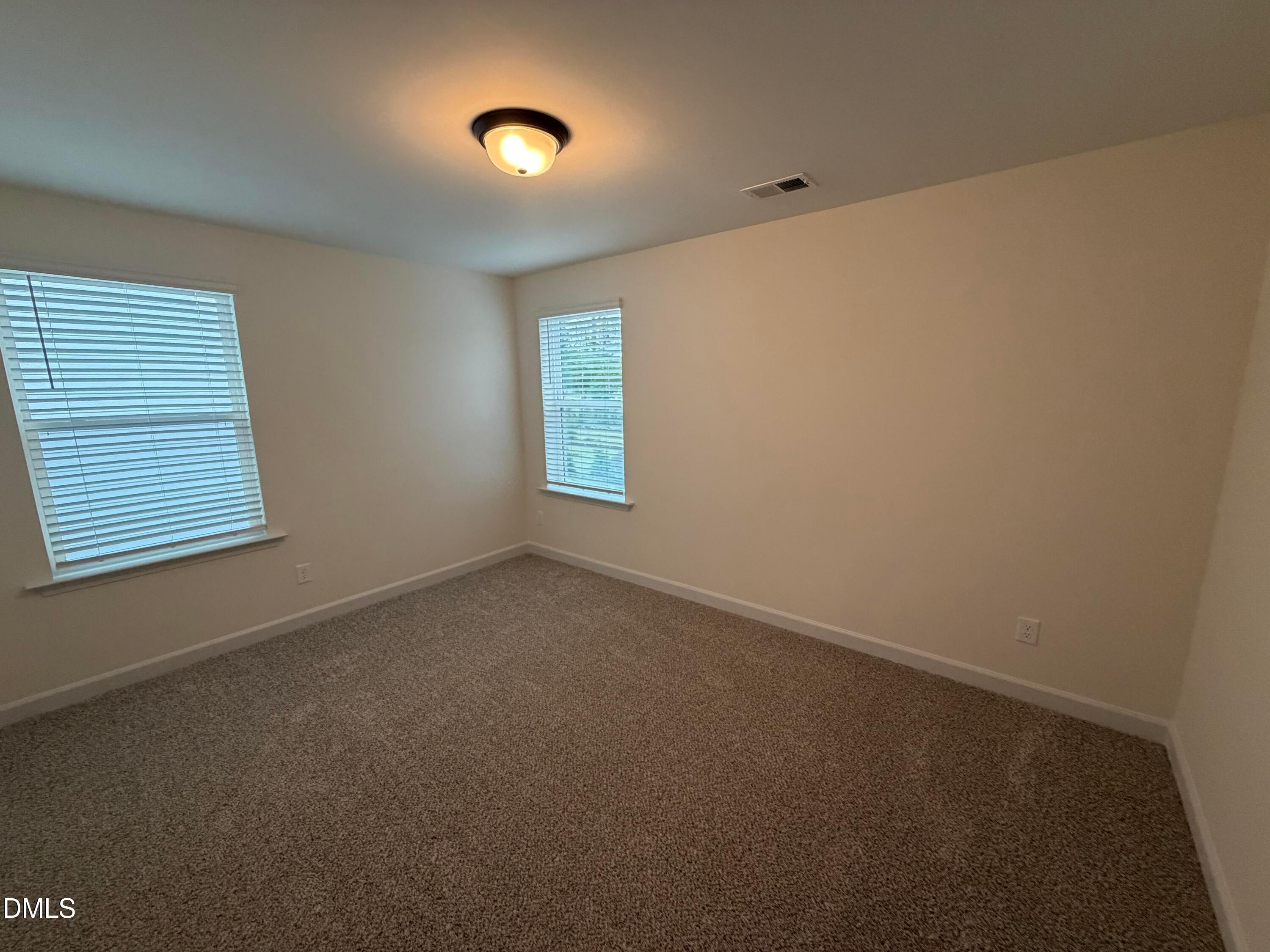 Bright carpeted bedroom with two windows, flush-mount lighting, and neutral walls in Davidson Homes The Ashport M, Wendell Ridge, NC