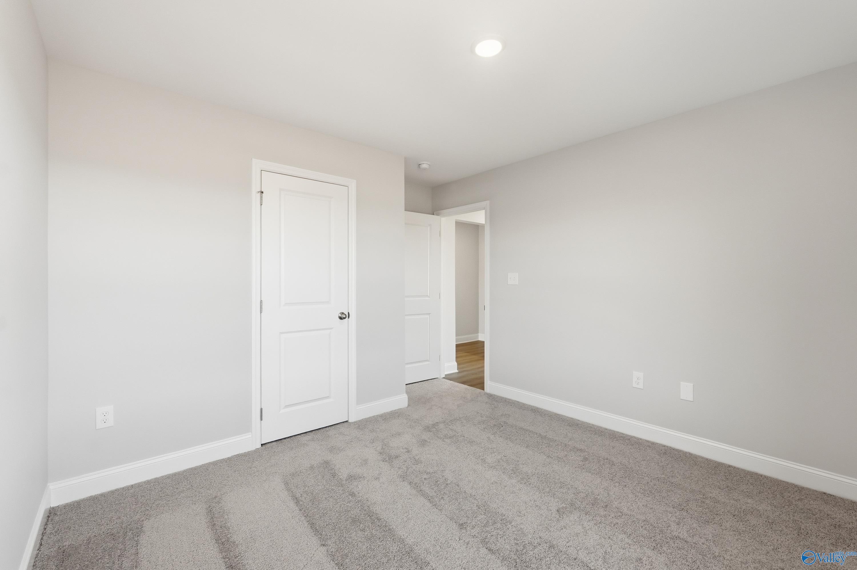 Empty secondary bedroom featuring gray walls, white doors, and plush carpet in Davidson Homes The Franklin, Heritage Lakes, Alabama