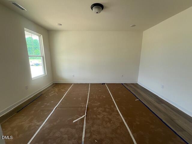 Spacious unfinished living area with wood-style flooring in The Hickory II B at Retreat at North Main, Lillington, NC.
