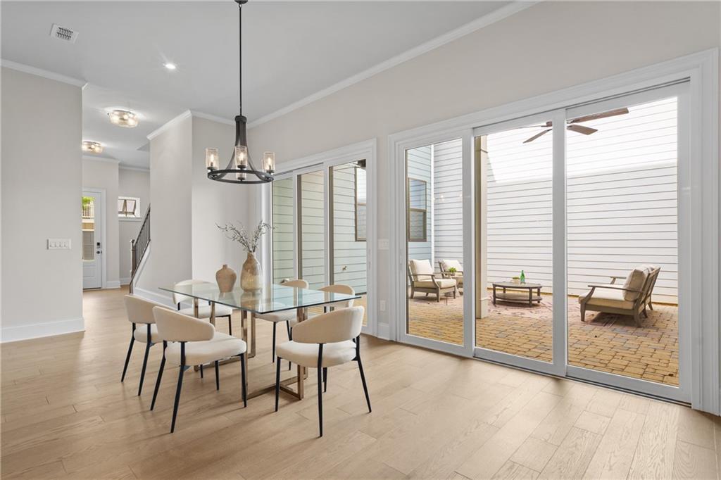 Elegant dining room with glass table, white chairs, and chandelier opening to patio in Davidson Homes The Seaside B, Woodstock, GA