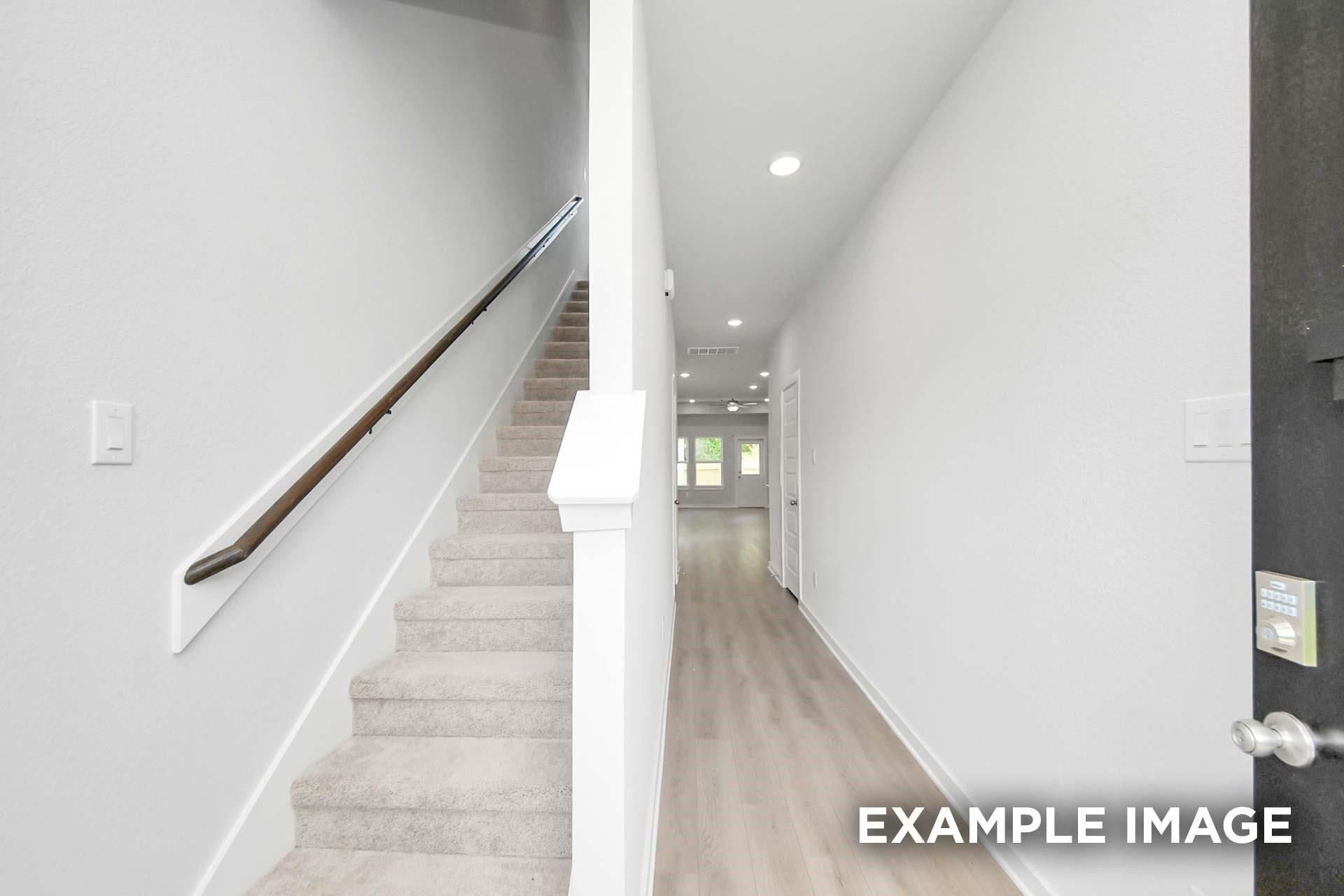 Carpeted staircase with wooden handrail and hardwood entry hallway in Davidson Homes The Blanco E, Magnolia, Texas
