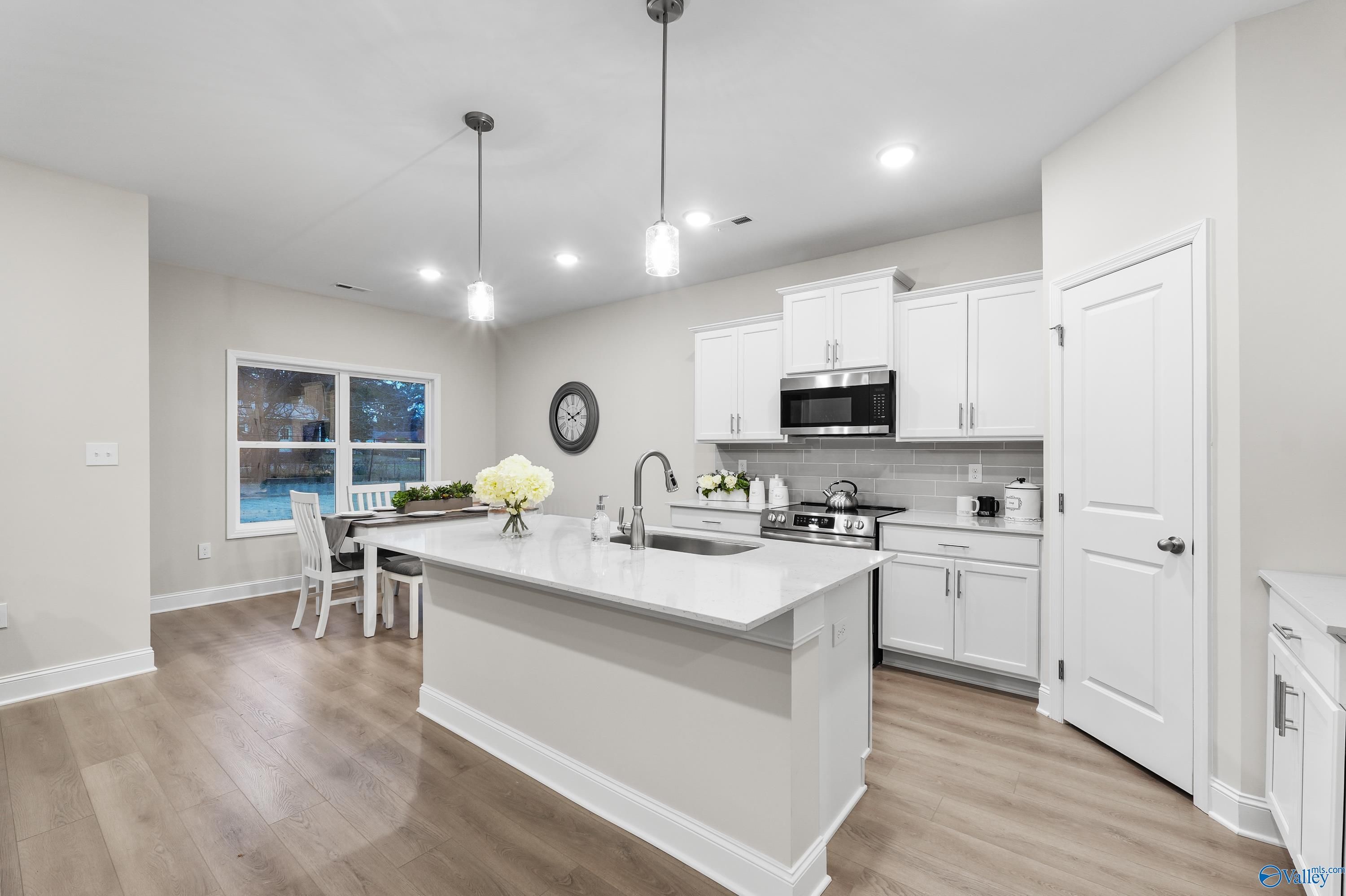 Modern white kitchen island with stainless appliances and pendant lights in The Asheville C 3-bedroom home, Huntsville, Alabama
