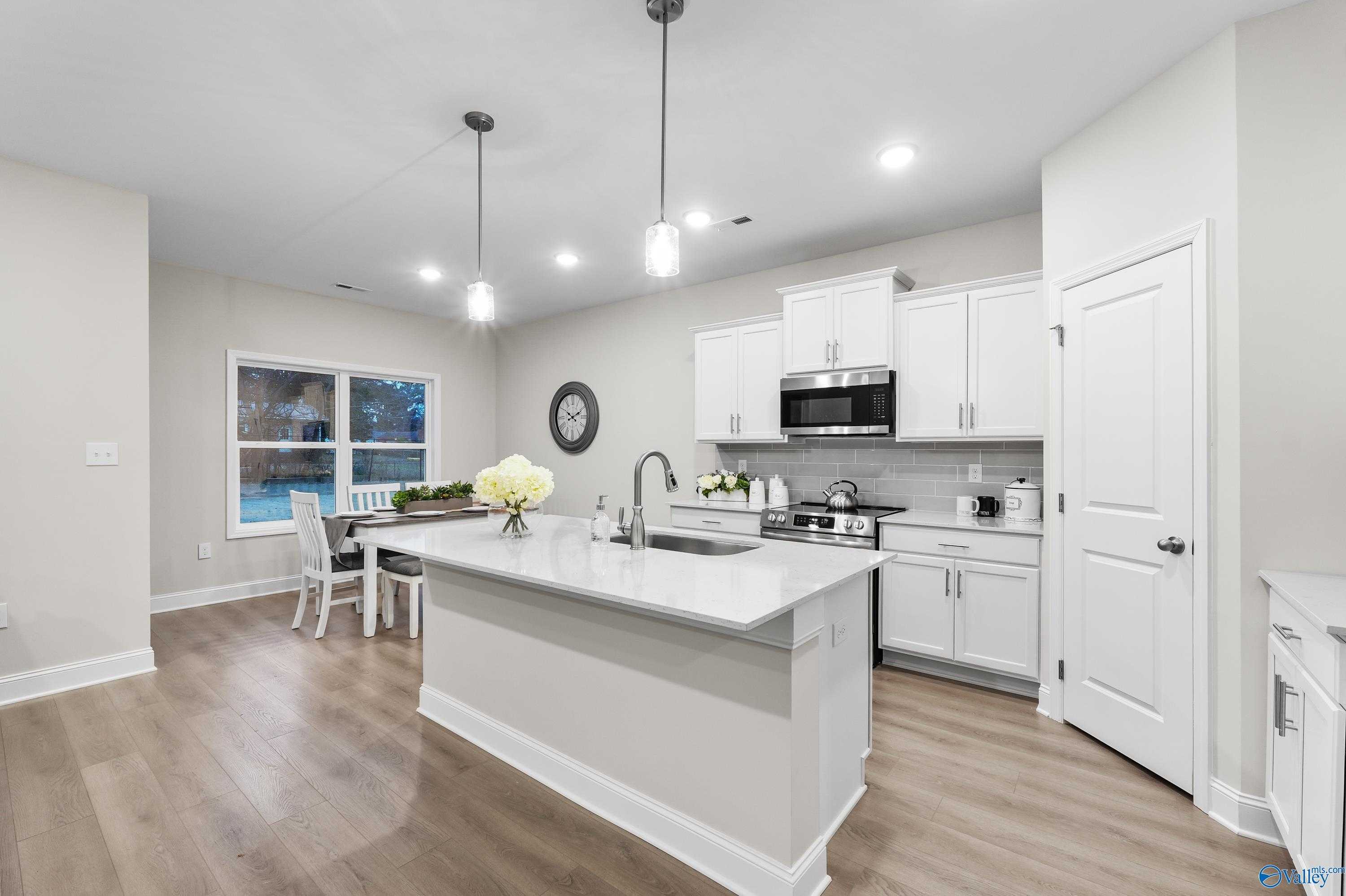 Modern open-concept kitchen with white shaker cabinets, quartz island, stainless appliances in Davidson Homes The Asheville C, Huntsville AL