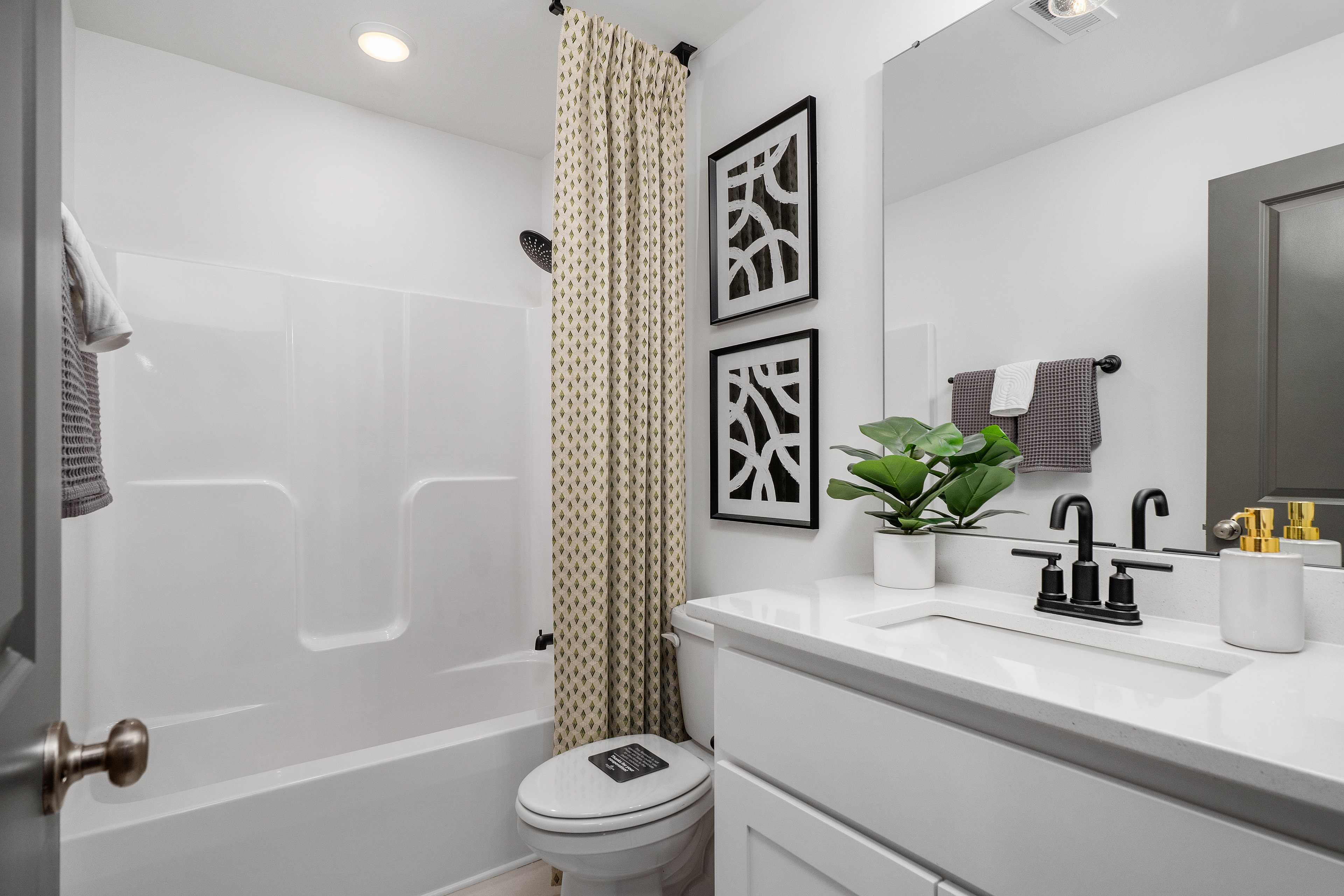 Spacious modern bathroom at Barnett's Crossing in Madison AL with white tub, walk-in shower, vanity sink, and geometric wall art