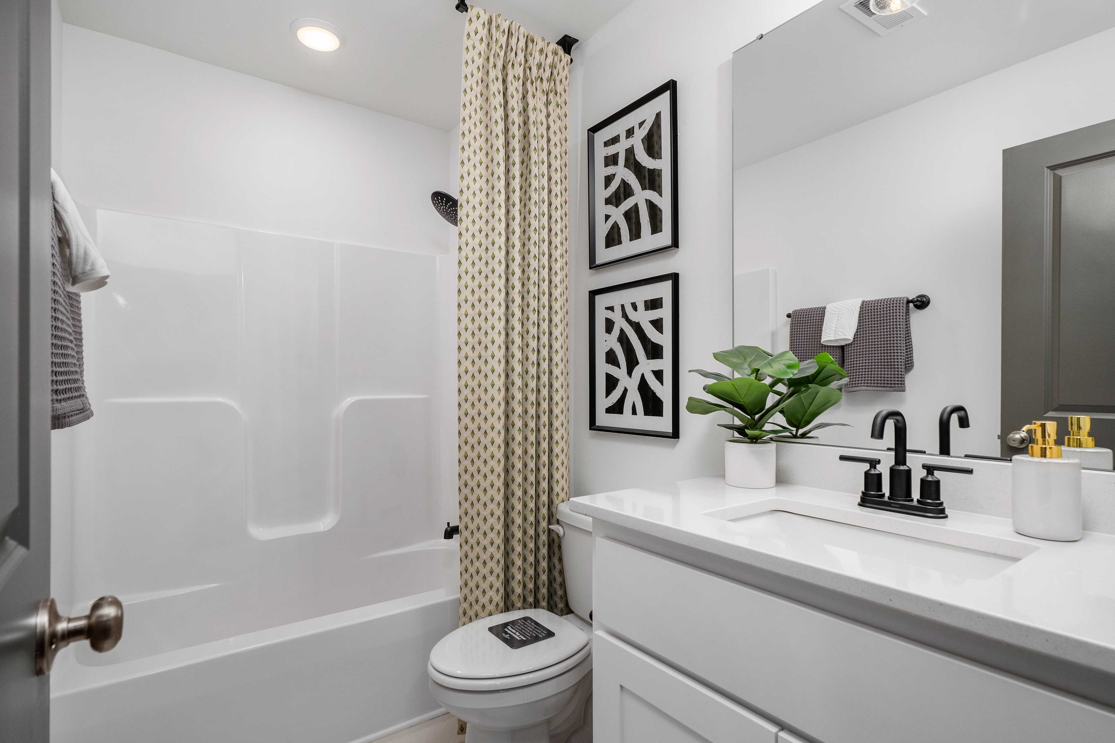 Spacious modern bathroom at Barnett's Crossing in Madison AL with white tub, walk-in shower, vanity sink, and geometric wall art