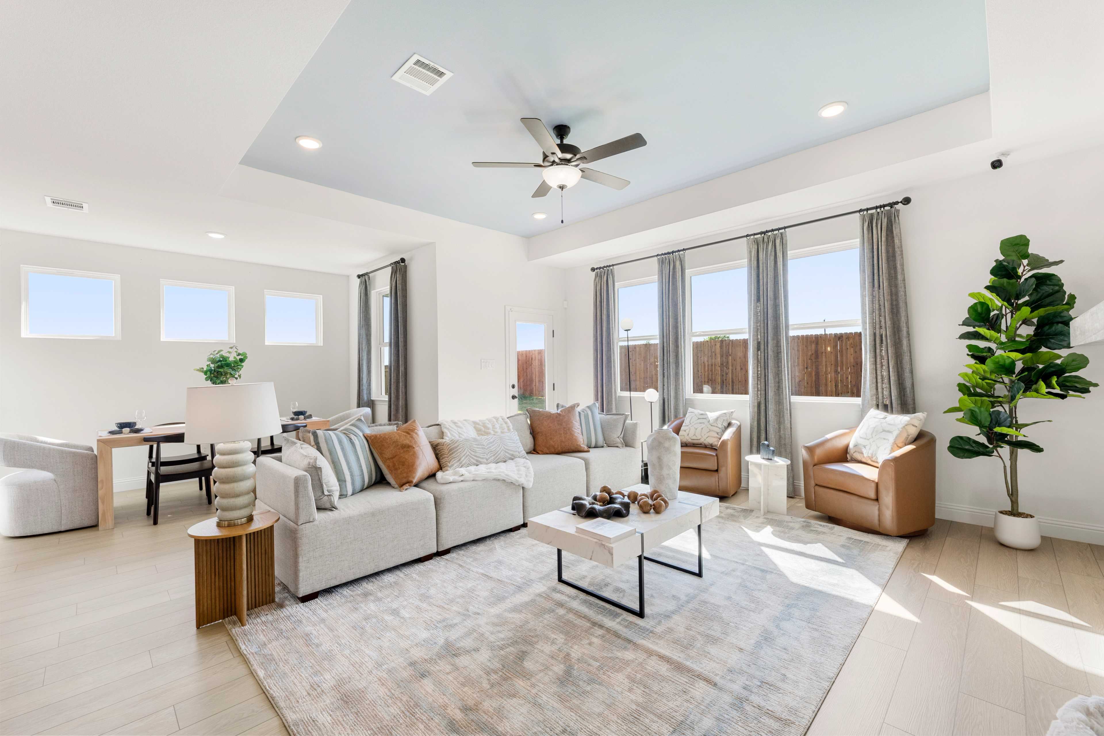 Spacious living room at Meadow Ridge Estates in Josephine Texas with white sectional sofa large windows blue ceiling and wood floors