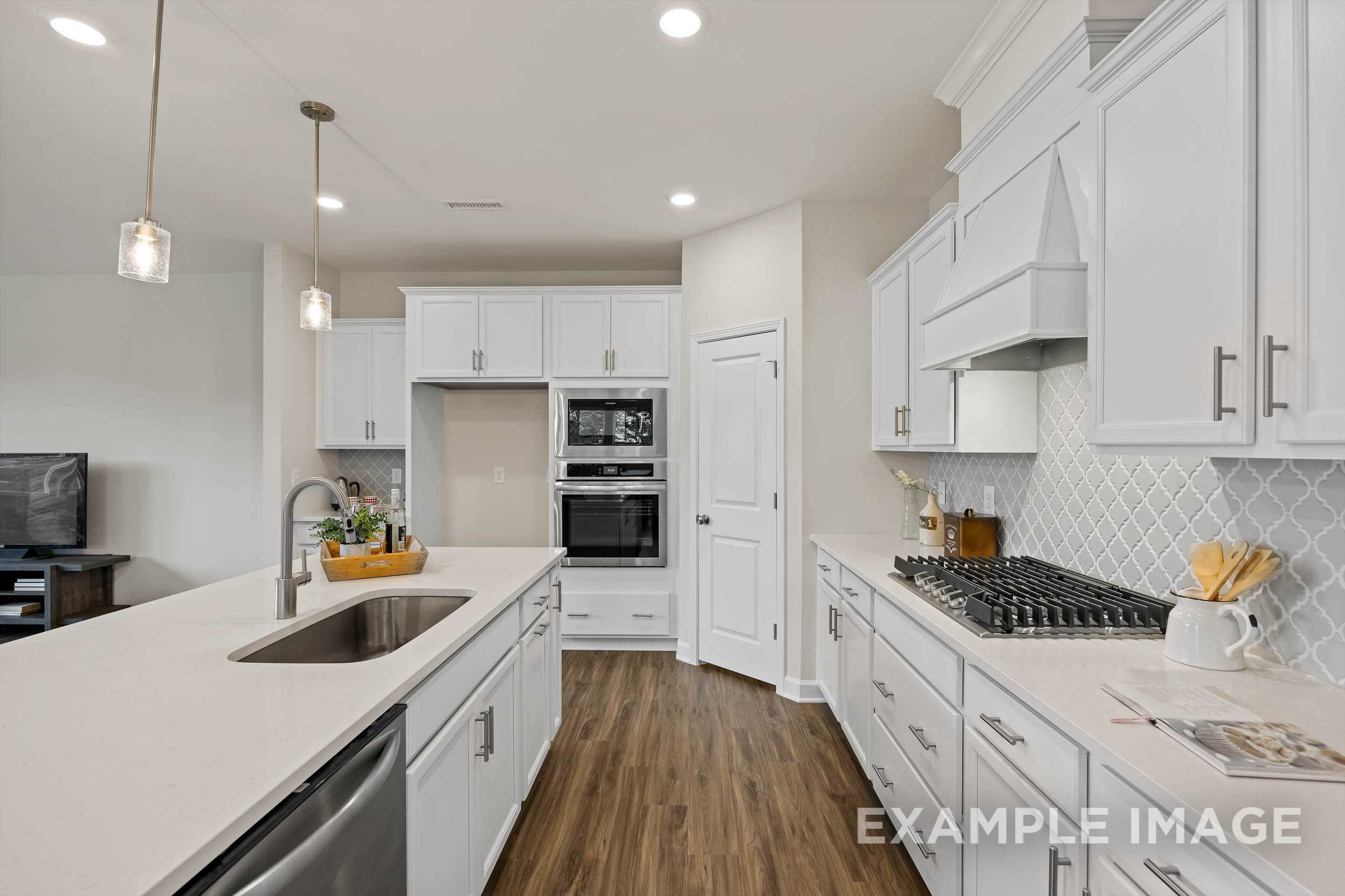 Spacious modern kitchen in The Preston B featuring white shaker cabinets, quartz island sink, and stainless steel appliances