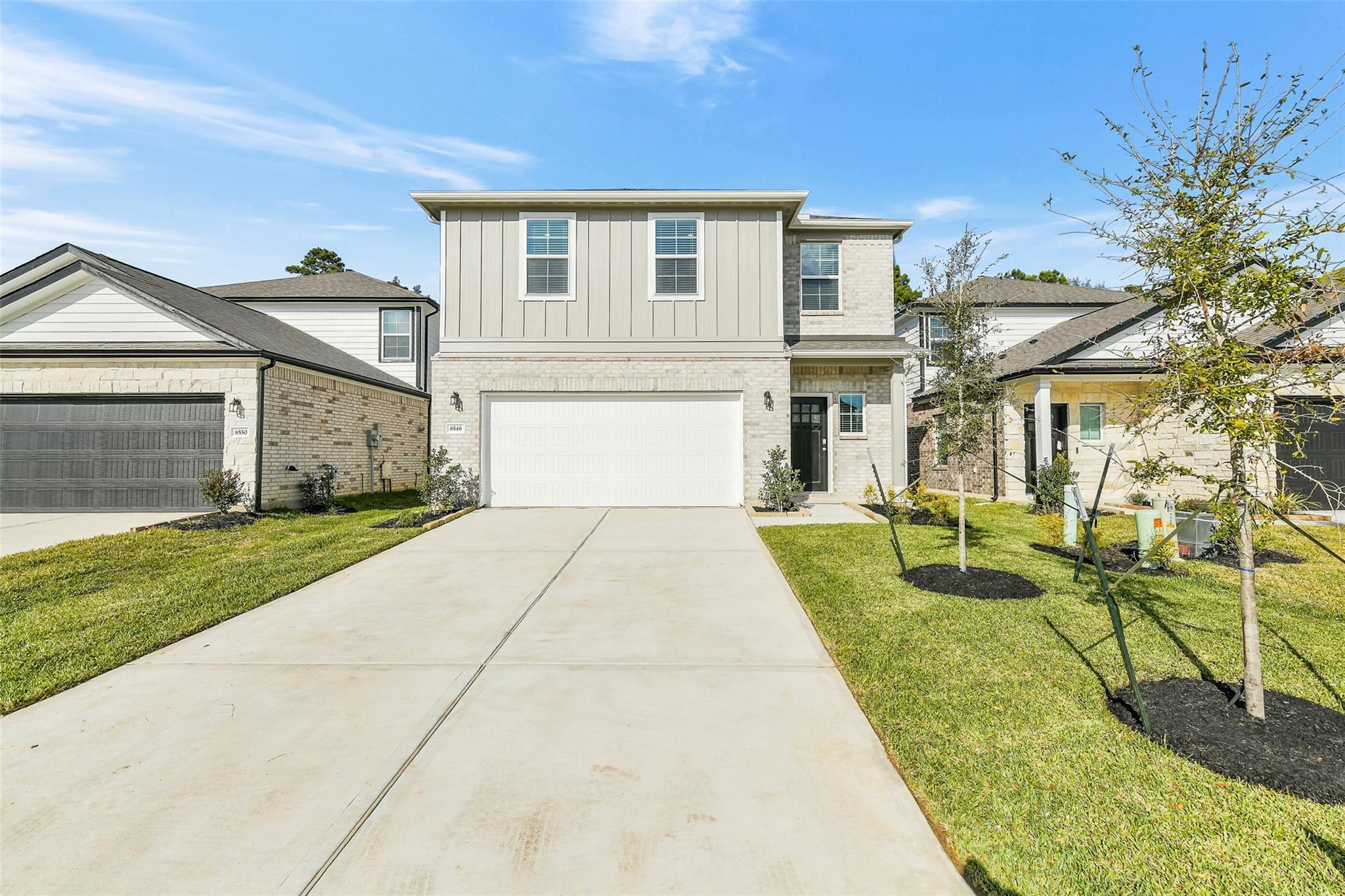 Two-story 5-bedroom home with 2-car garage, brick accents, and landscaped driveway in Lakes at Black Oak, Magnolia, Texas