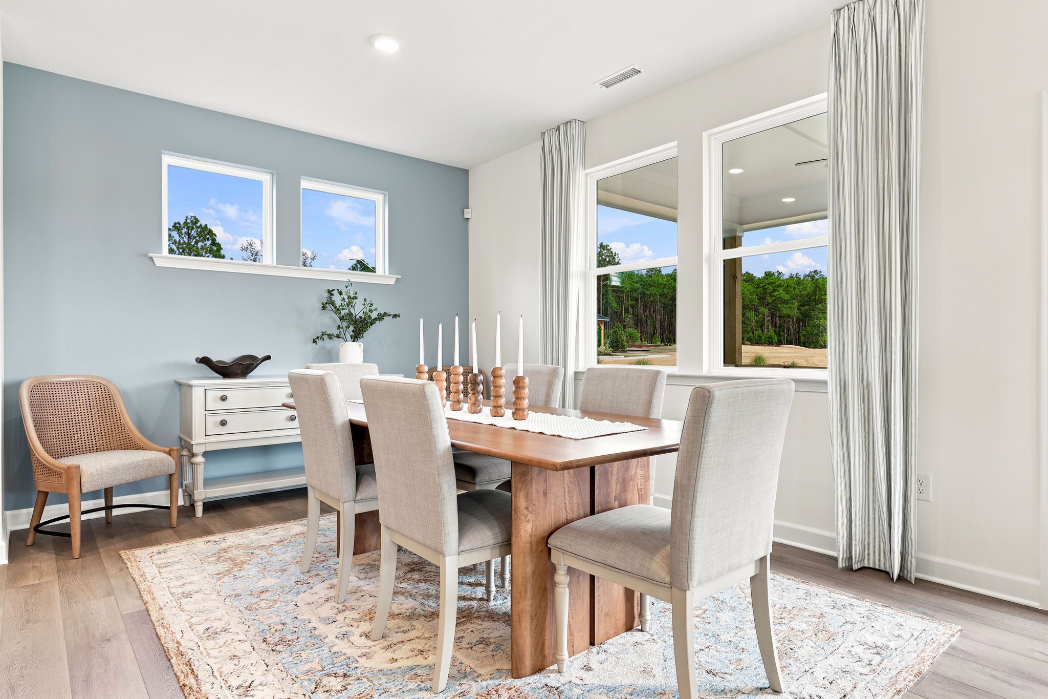 Bright dining room at Montrose in Aberdeen, NC by Davidson Homes featuring a wooden table and blue accent wall.