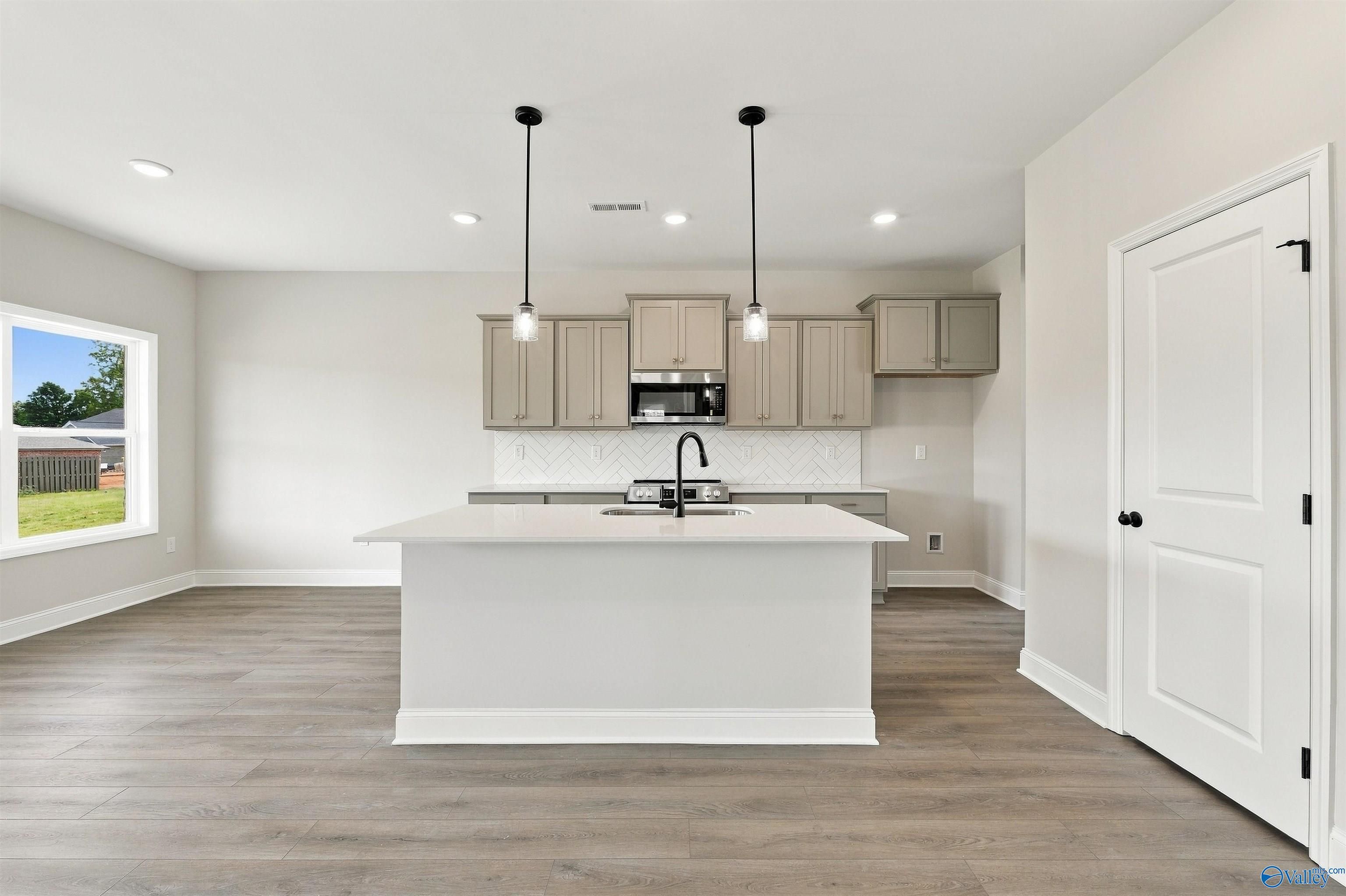 Open-concept kitchen with large center island, pendant lights, and gray shaker cabinets in Davidson Homes The Shelby A, Athens, AL