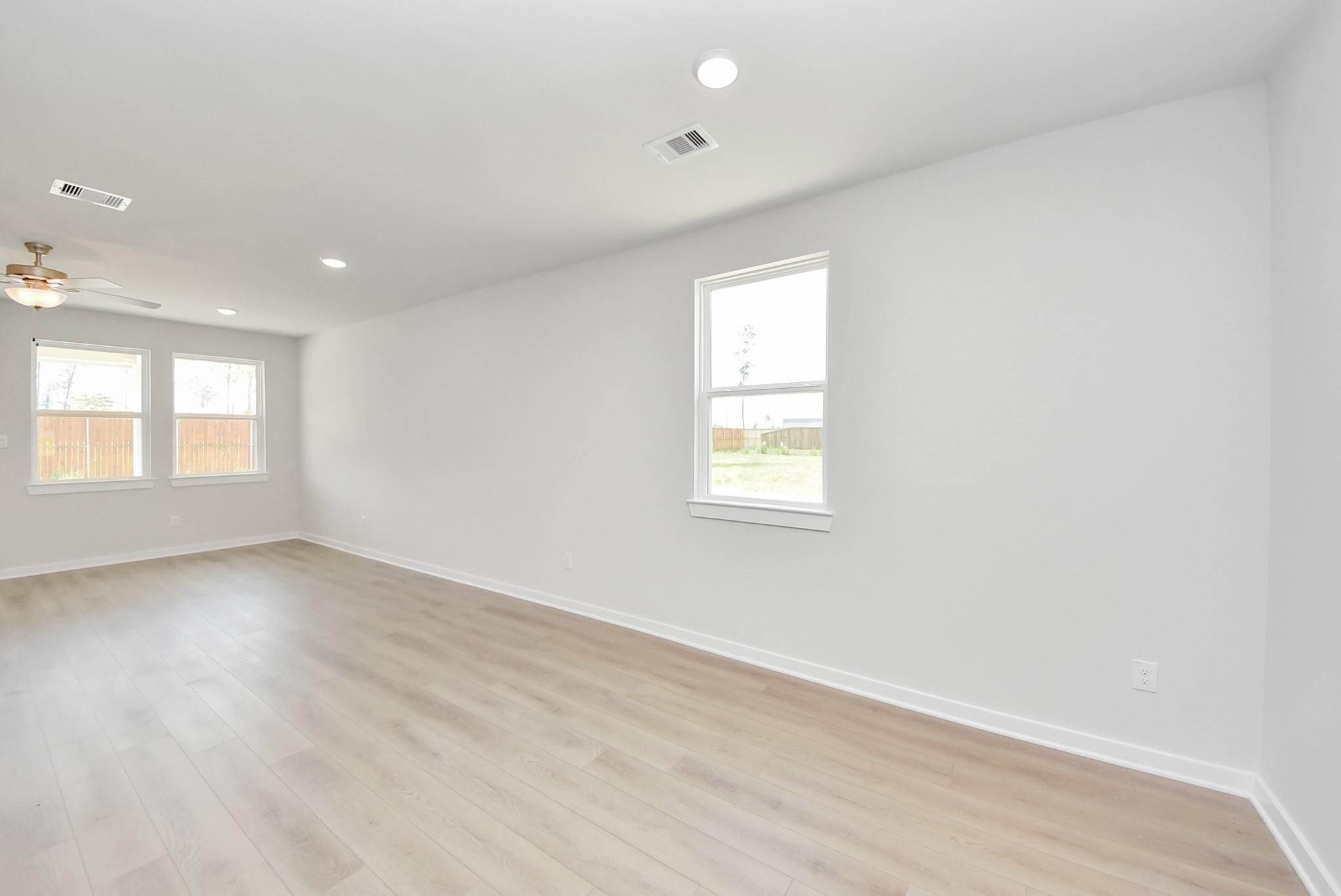 Spacious, bright living area with wood-style flooring in The Blanco F floor plan at Spring Branch Crossing, Conroe, Texas.